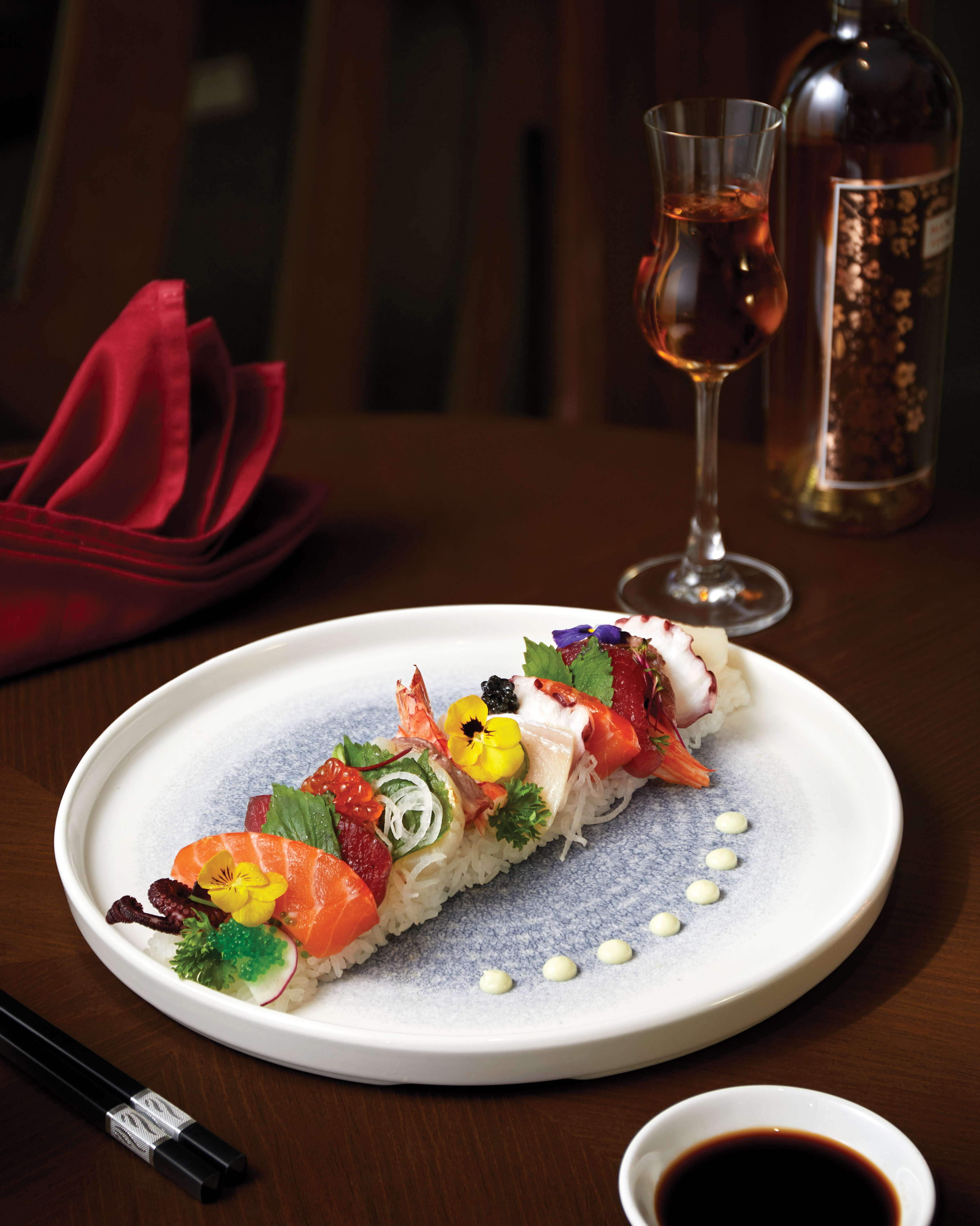 Gourmet sushi and sashimi display with salmon, octopus, roe, and wine.