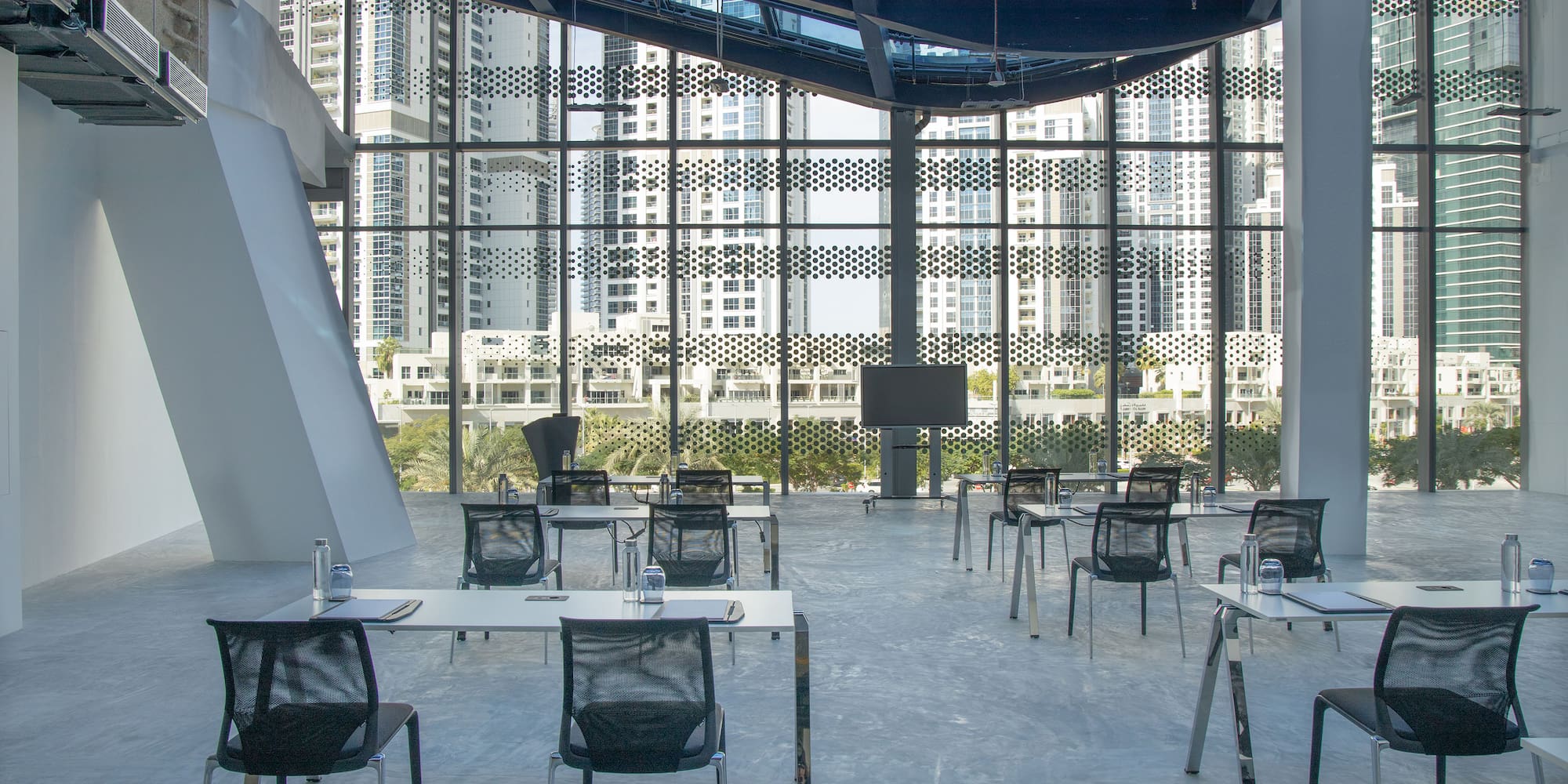a room with tables and chairs in front of a large window