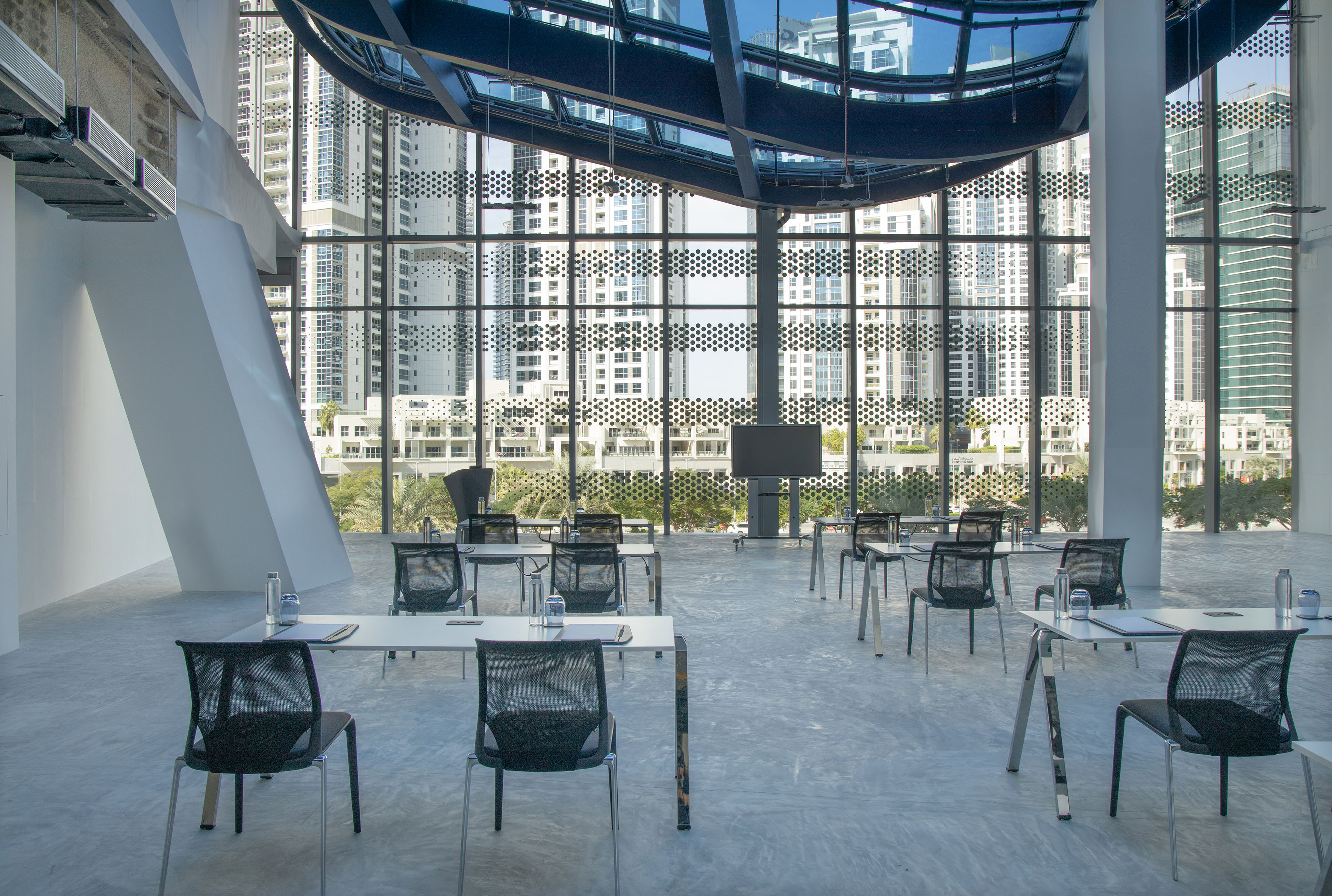 Modern training room, individual desks, city skyline view, large screen.