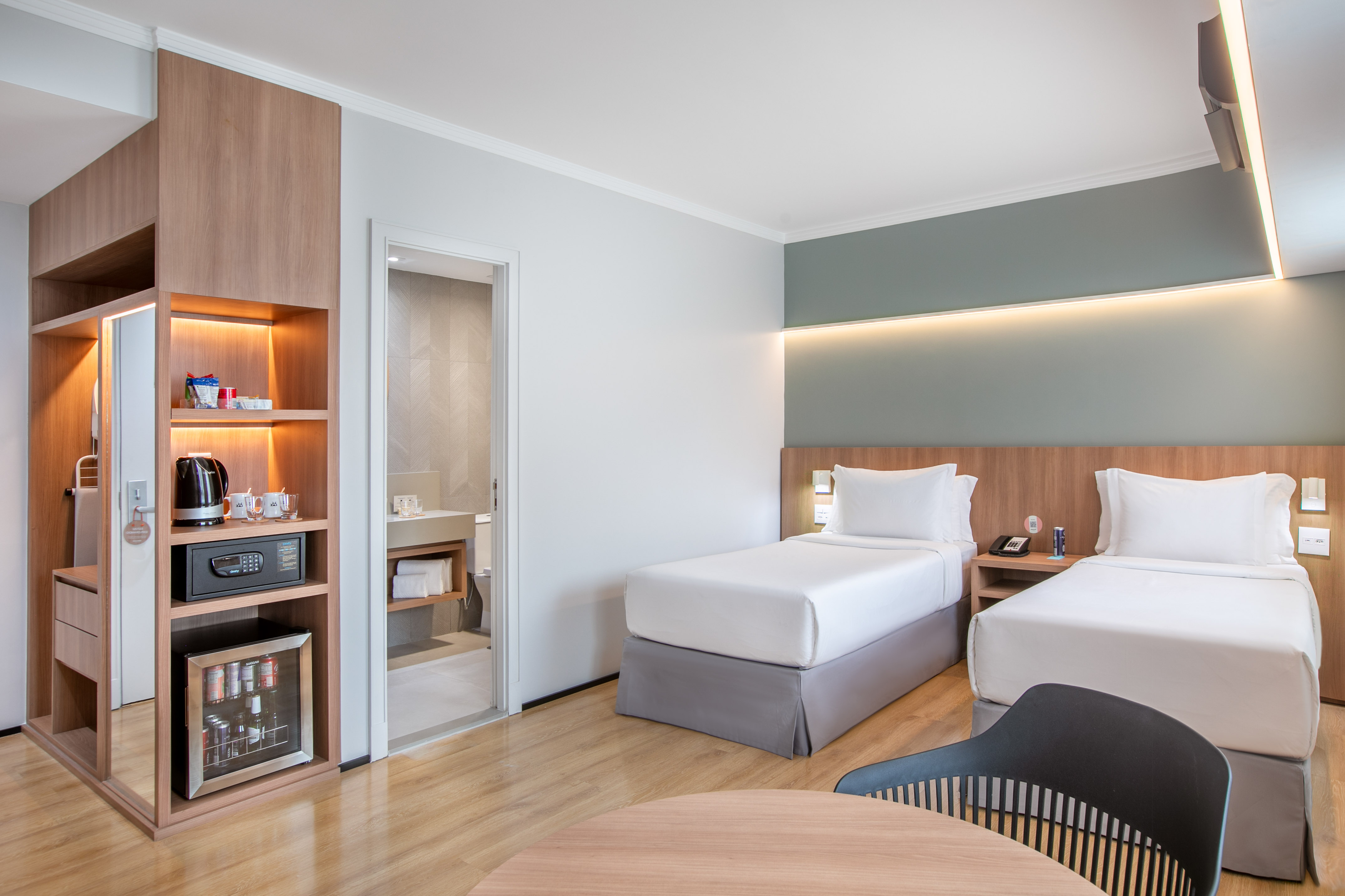 Modern hotel guest room with two twin beds, wood furnishings, and in-room amenities.