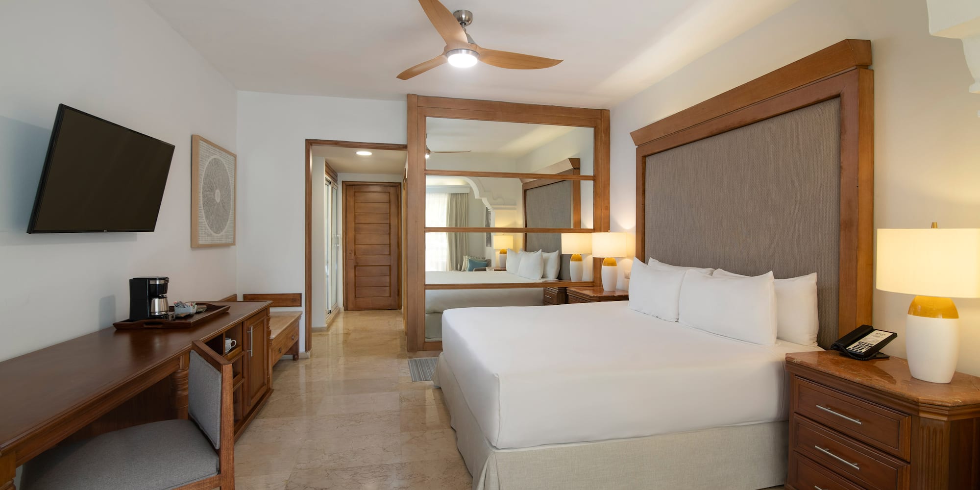 a room with a bed and a desk and a fan