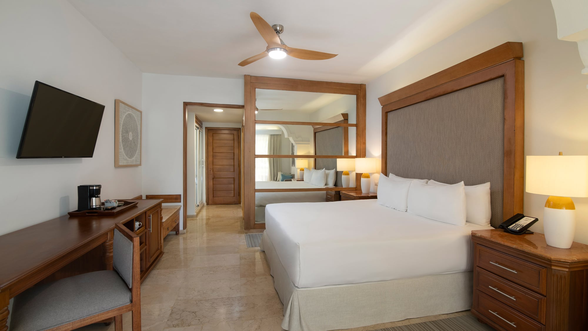 a room with a bed and a desk and a fan