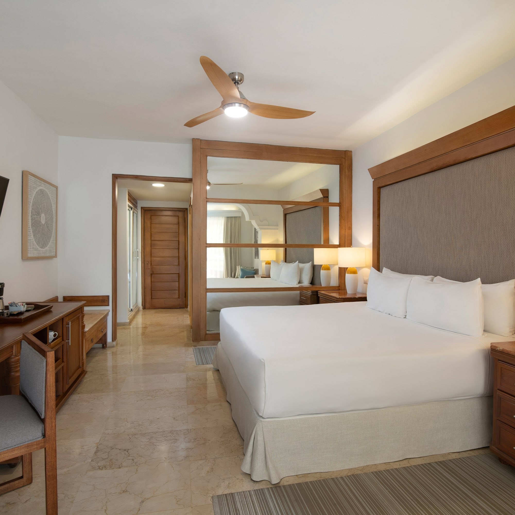 a room with a bed and a desk and a fan