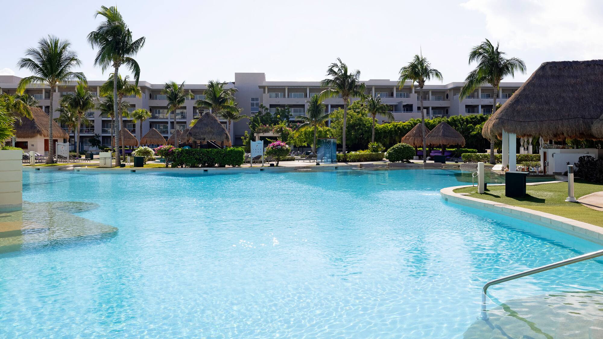 a pool with palm trees and a building in the background