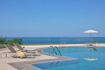 a pool with chairs and umbrellas by the ocean