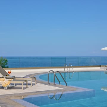 a pool with chairs and umbrellas by the ocean