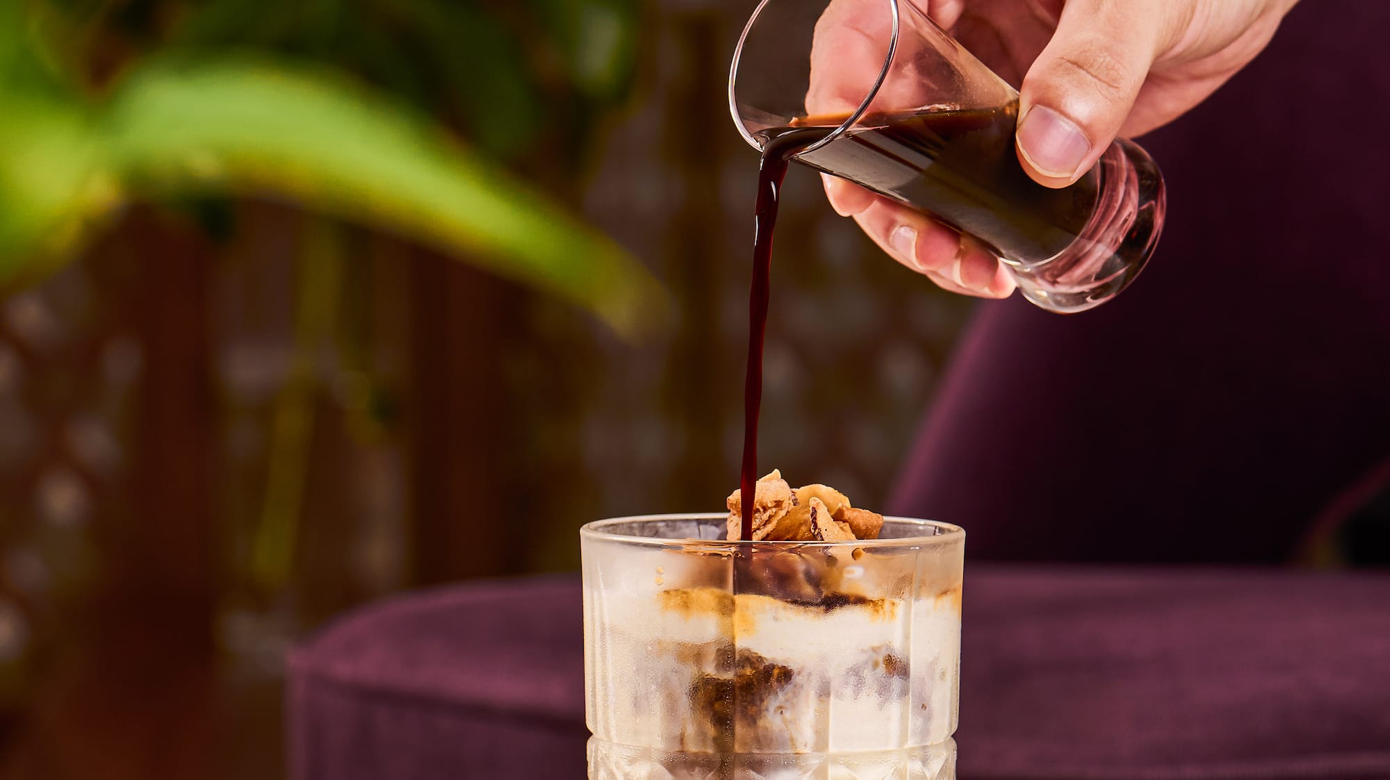 a person pouring a drink into a glass