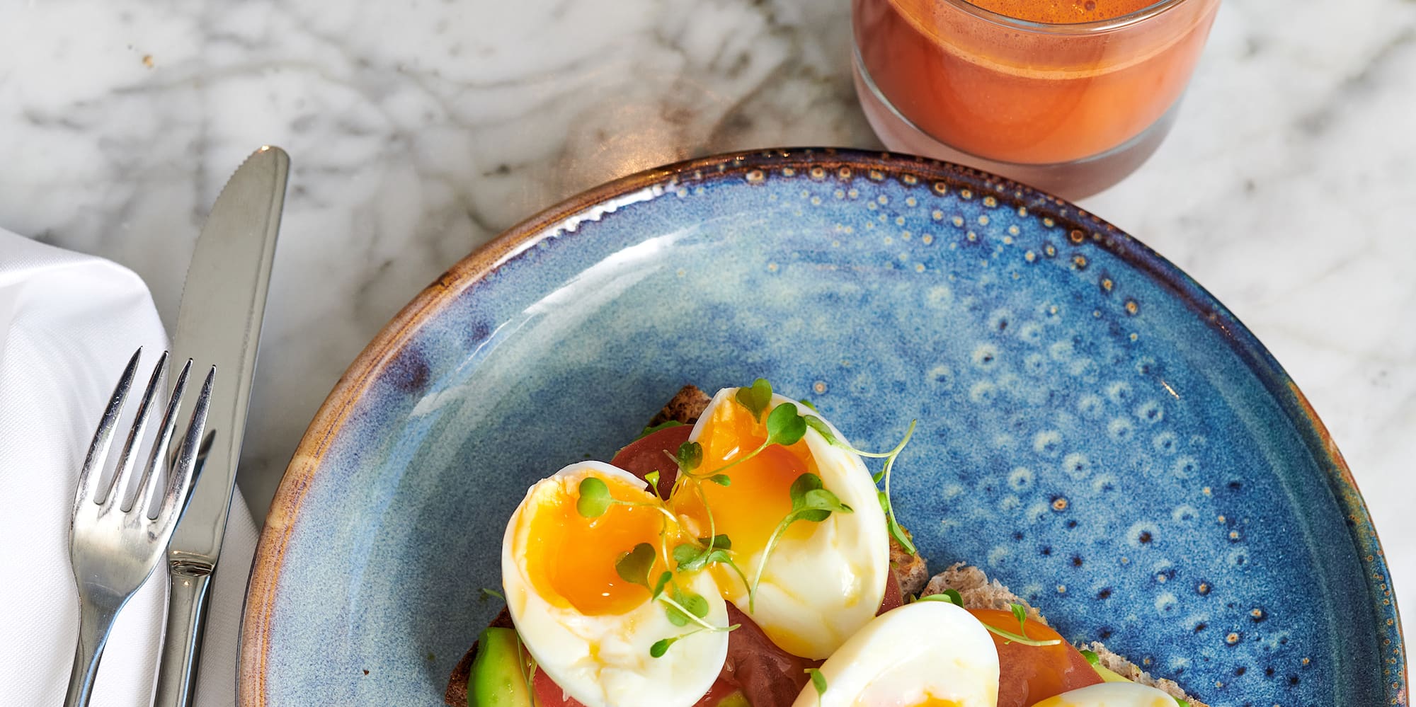a plate of food with a glass of juice and a fork