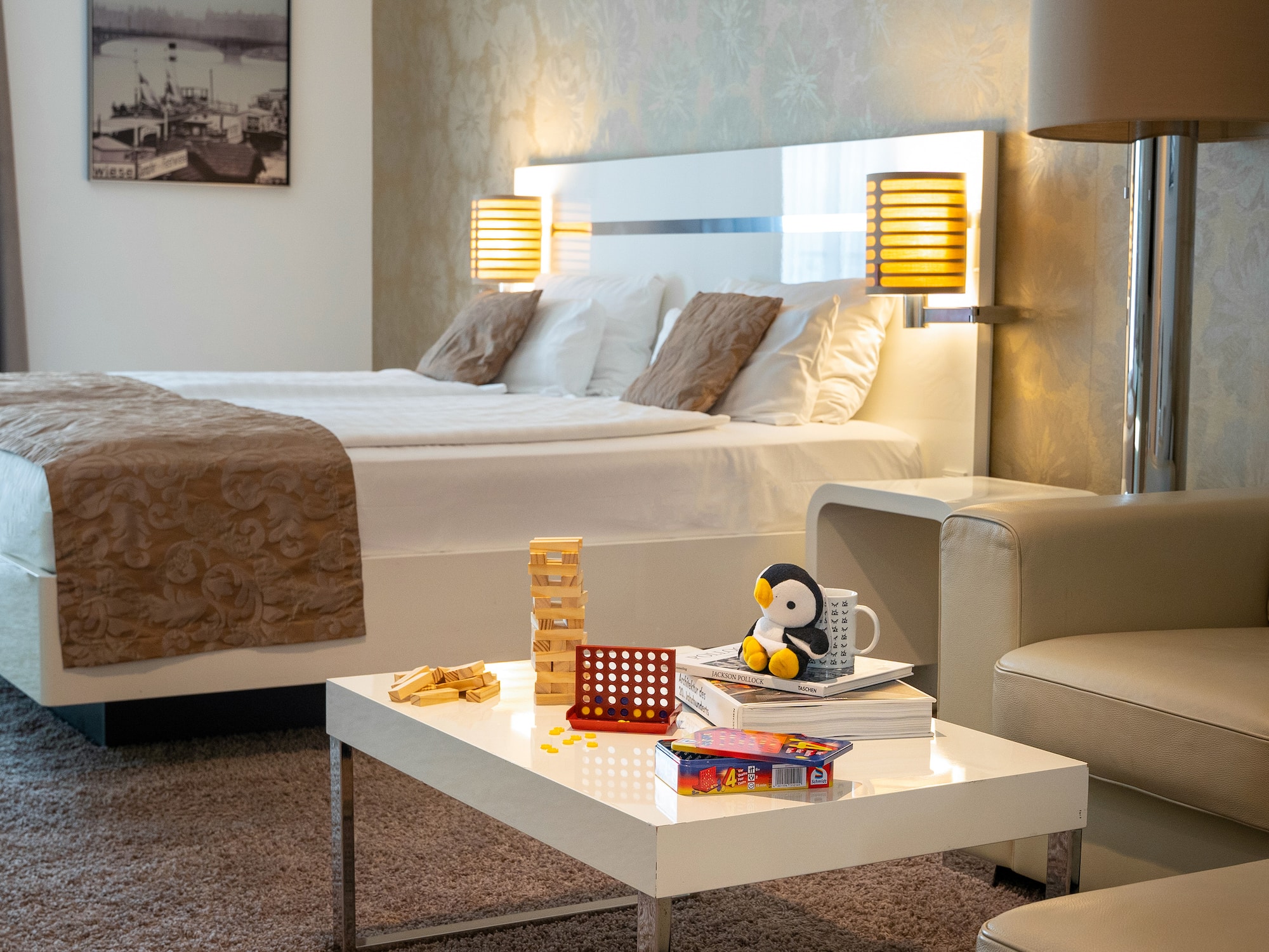 Modern hotel room with bed, coffee table, board games, and relaxing lounge area.