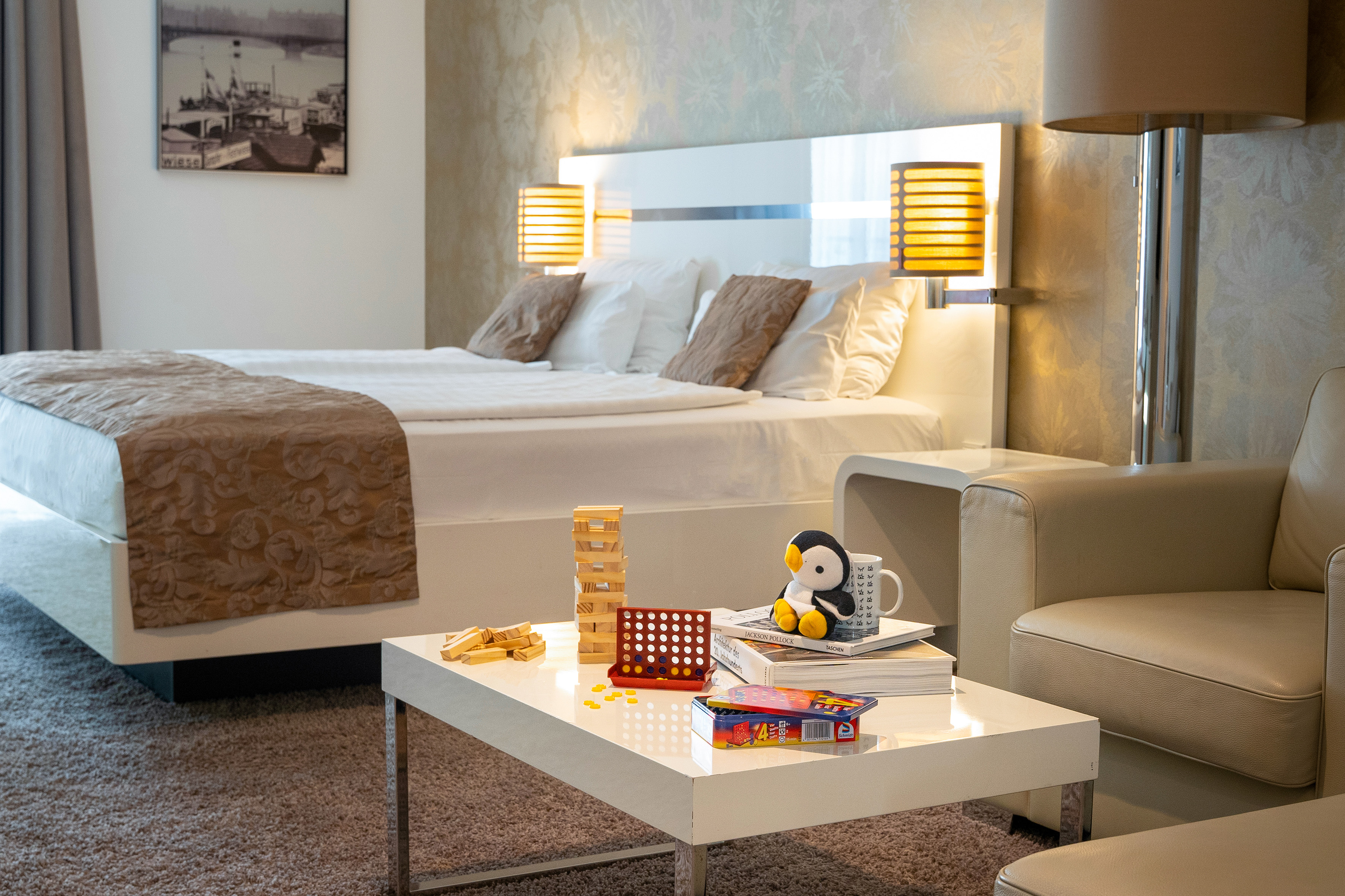 Modern hotel room with bed, coffee table, board games, and relaxing lounge area.