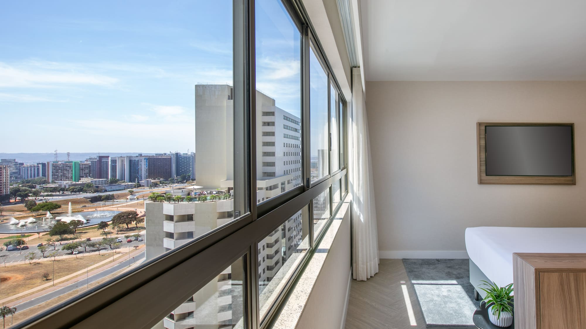 Modern hotel room with panoramic city view through expansive windows.