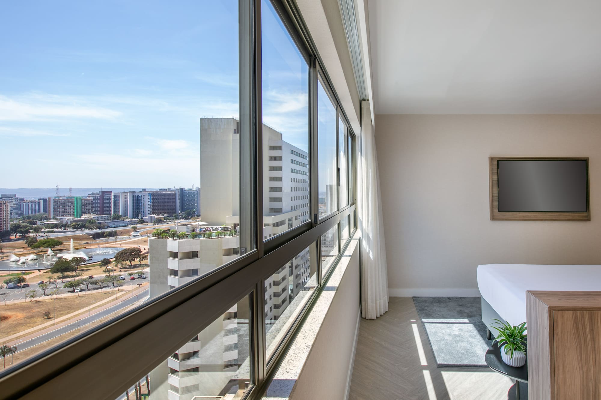 Hotel room interior with city skyline view through large panoramic windows.