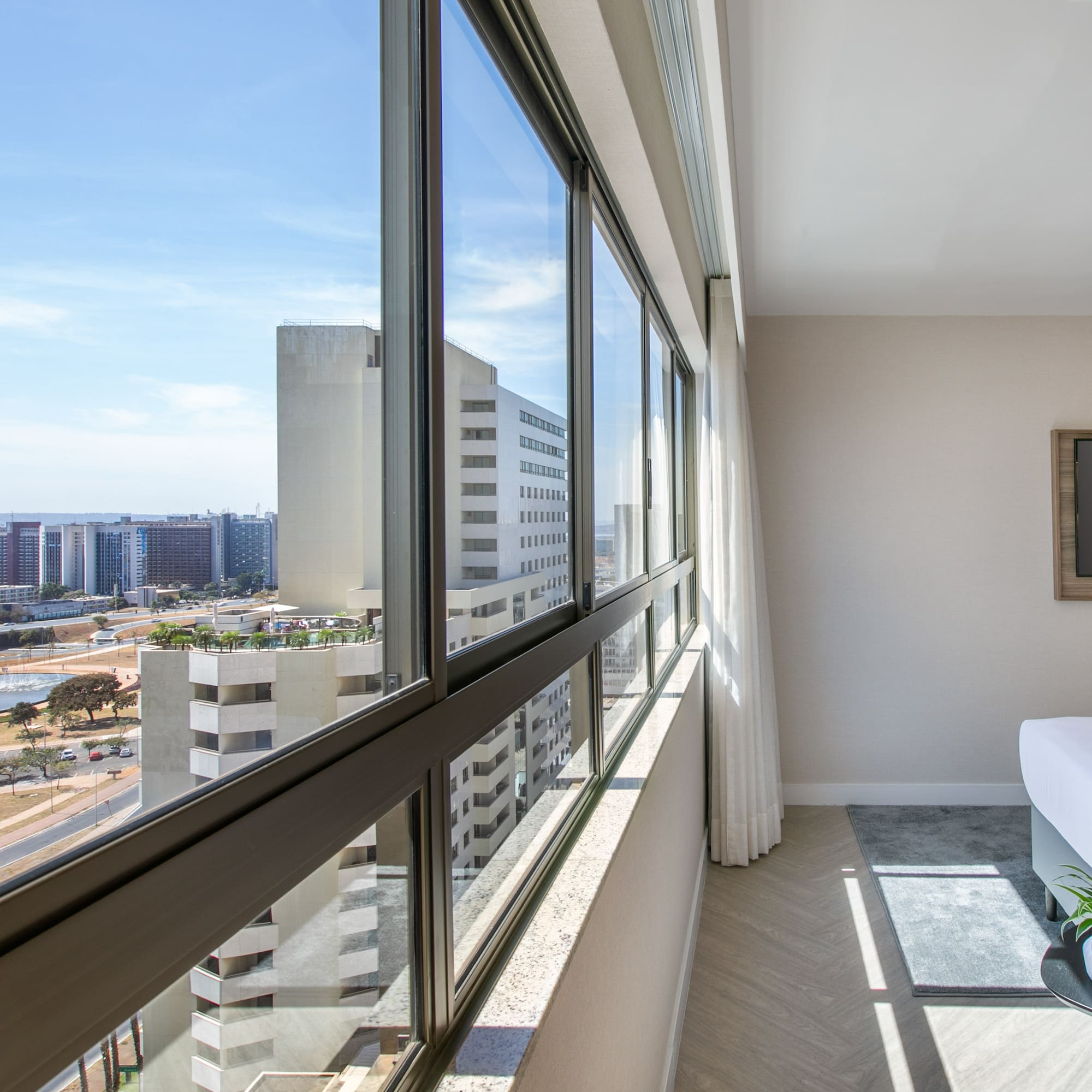 Hotel room interior with city skyline view through large panoramic windows.