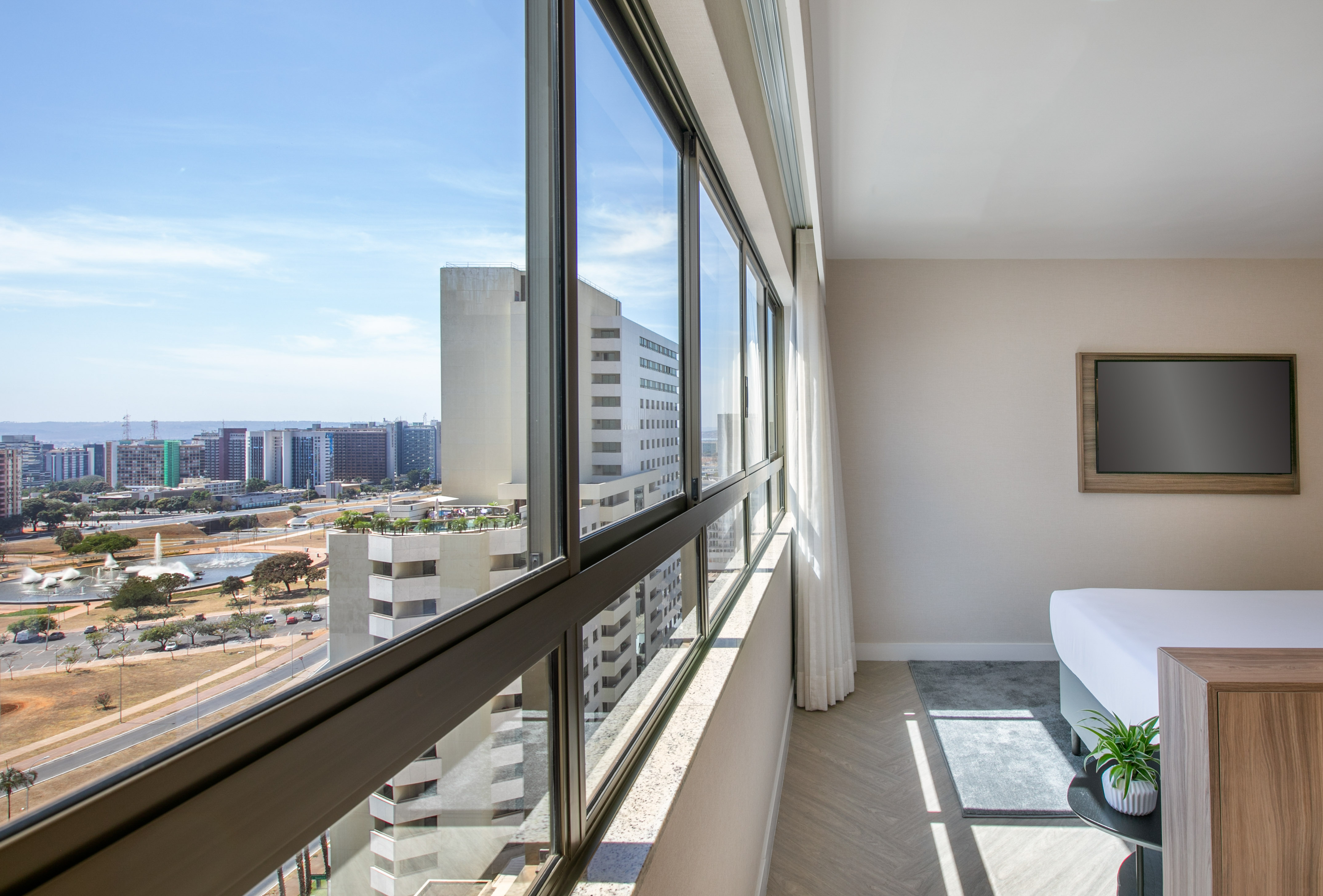 Hotel room interior with city skyline view through large panoramic windows.