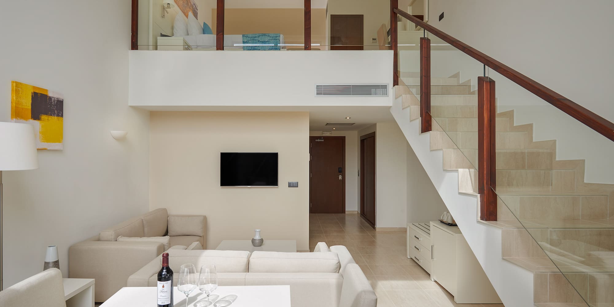 a room with a staircase and a table with food and wine