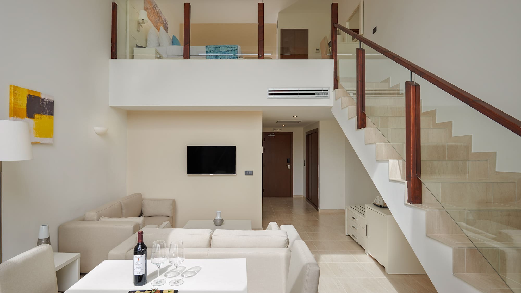 a room with a staircase and a table with food and wine