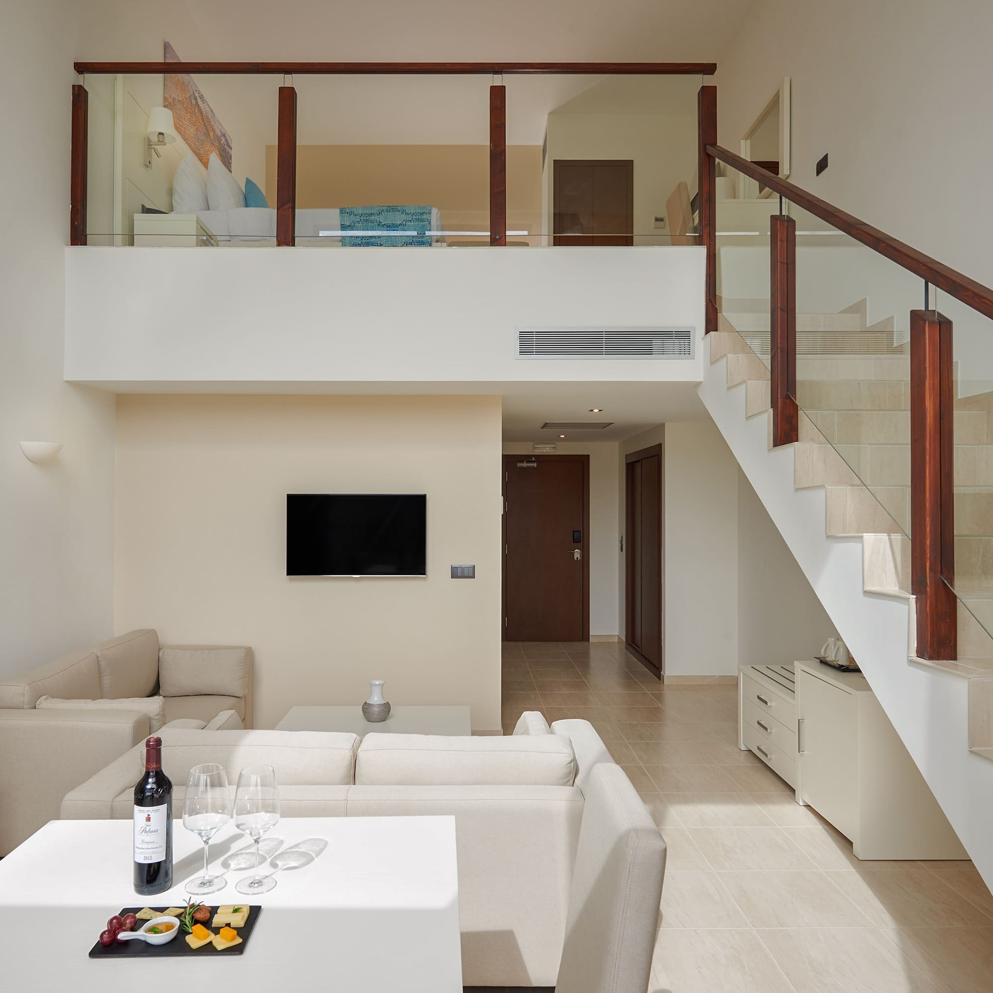 a room with a staircase and a table with food and wine