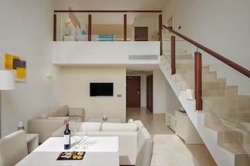 a room with a staircase and a table with food and wine
