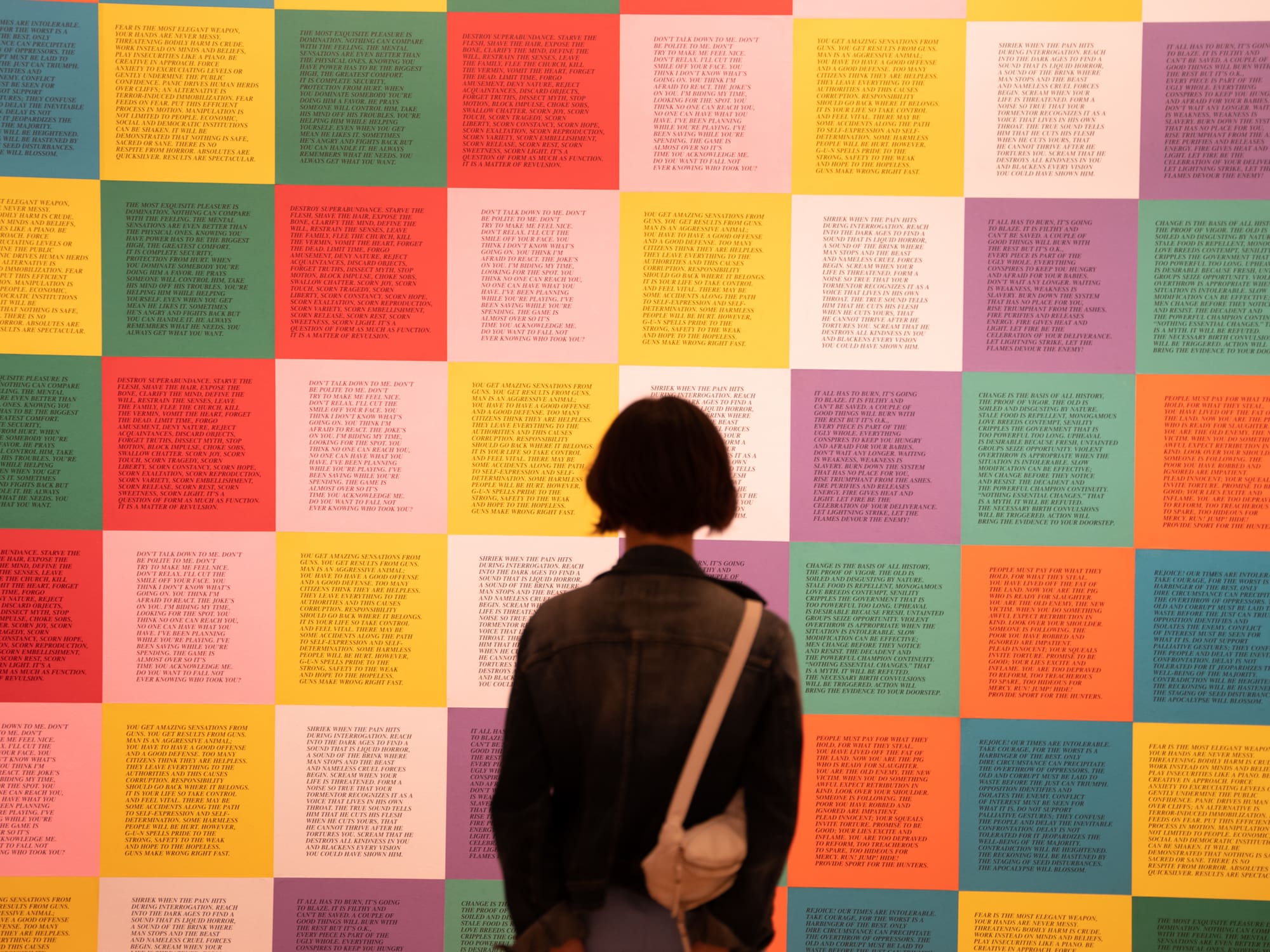 a person stands before a wall of vibrant squares