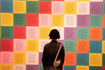 a person standing in front of a wall of colorful squares