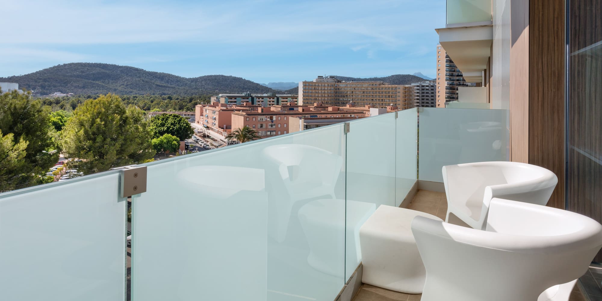 a balcony with white chairs and a glass railing