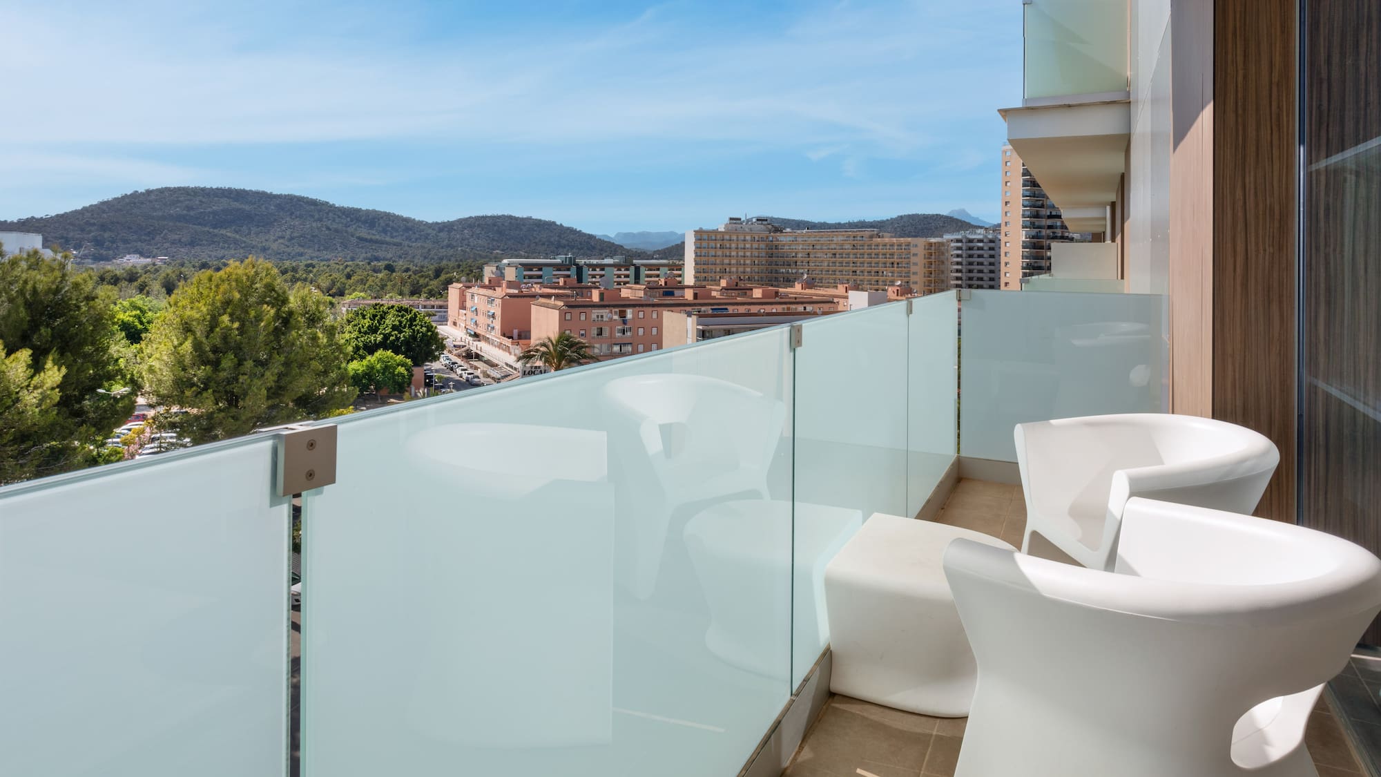 a balcony with white chairs and a glass railing