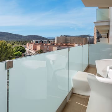 a balcony with white chairs and a glass railing