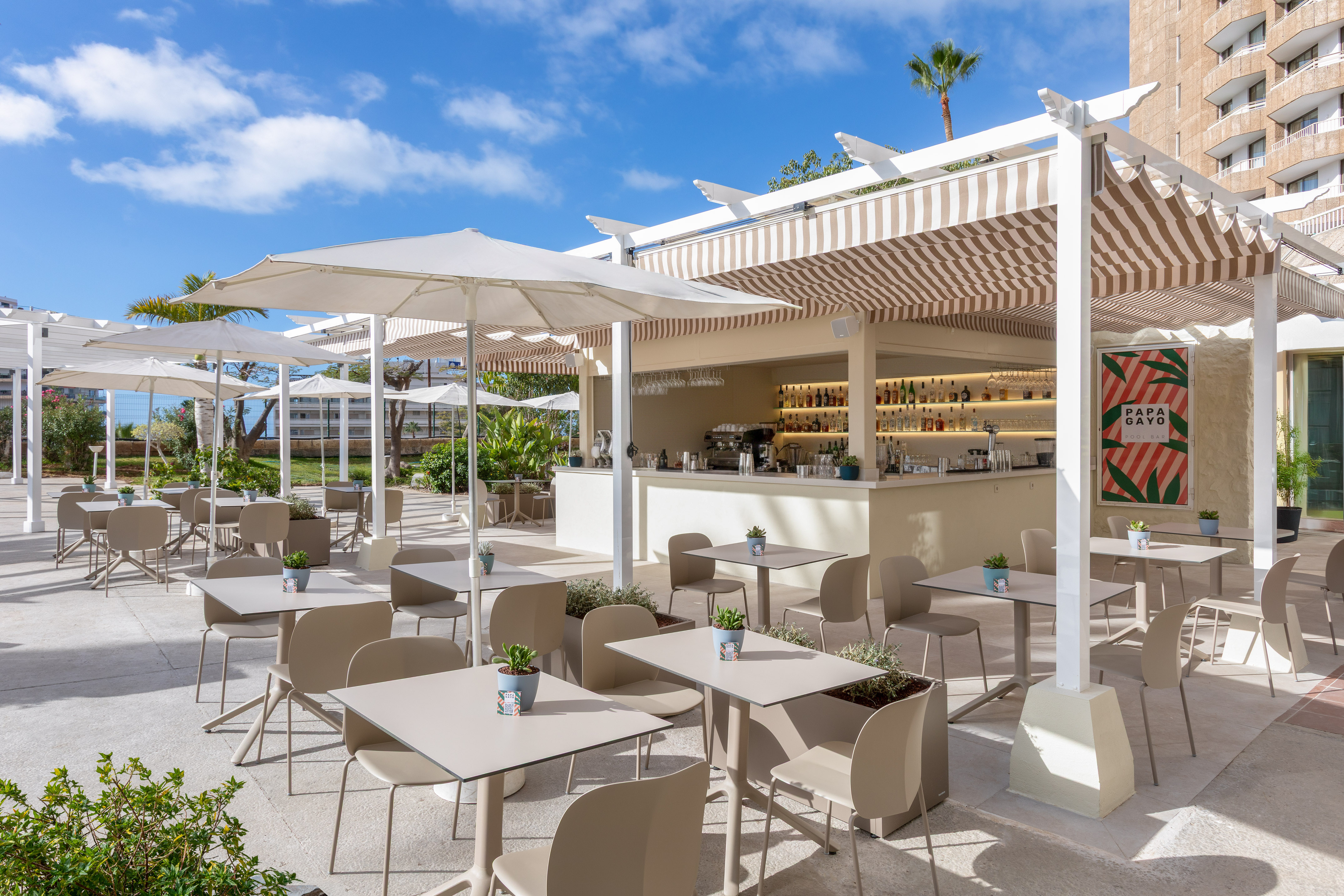 Papa Gayo Pool Bar outdoor terrace with tables, umbrellas, and striped awning.