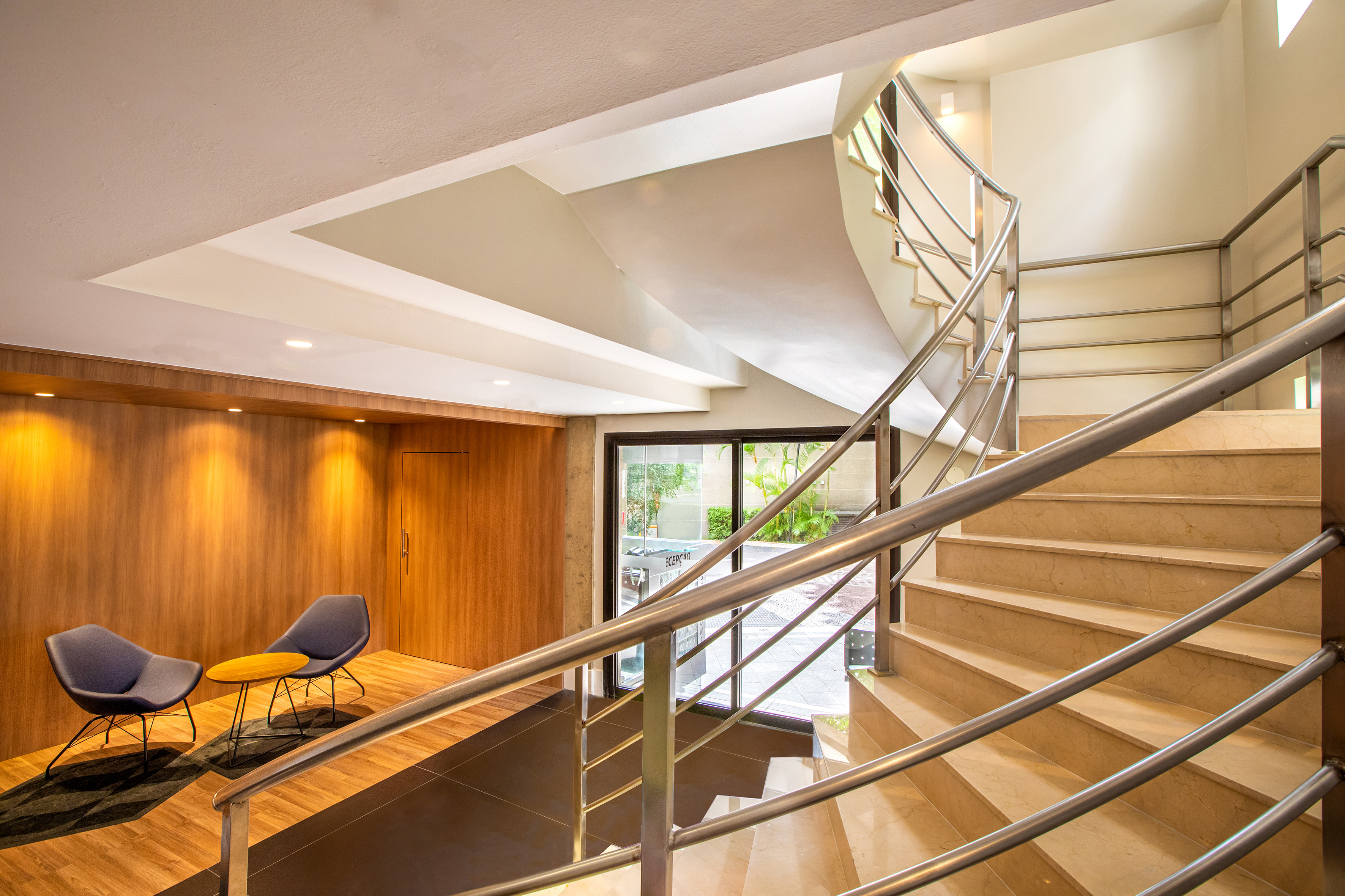 Modern lobby with a spiral marble staircase and a wood-paneled lounge area.