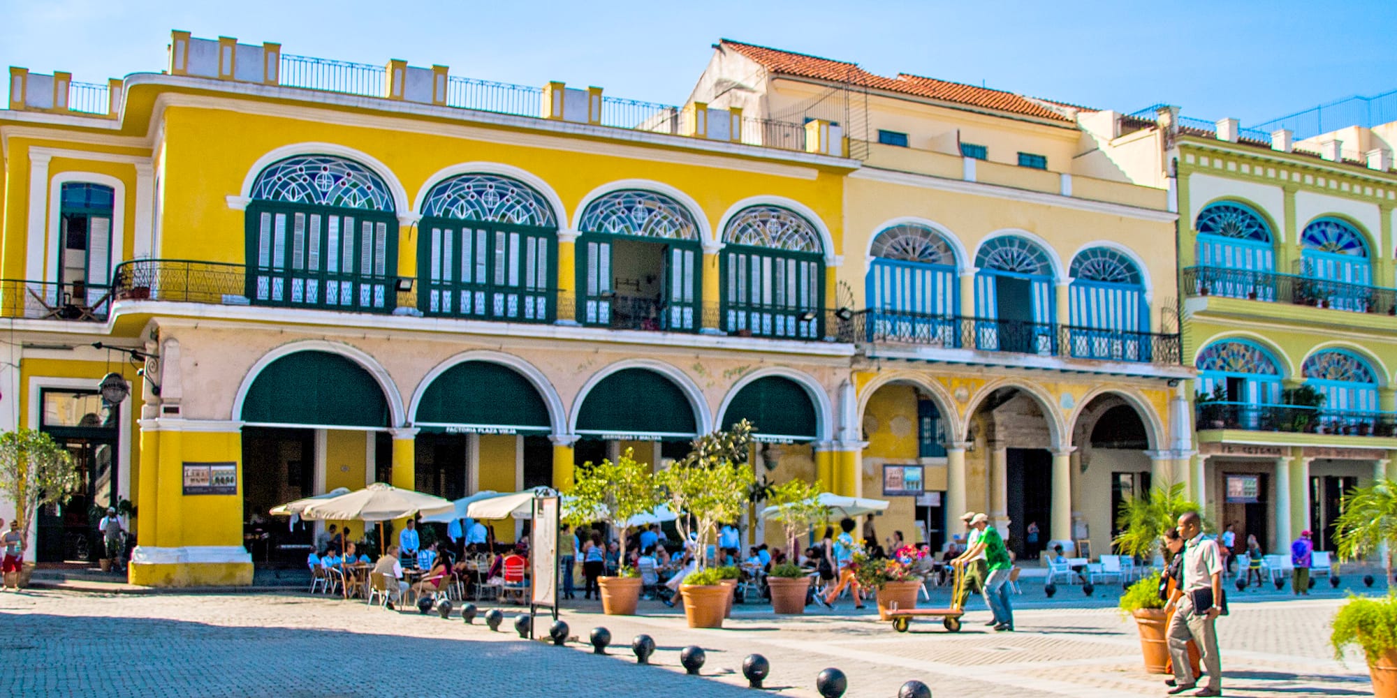 a yellow building with many people and a yellow building with many windows with Willemstad in the background