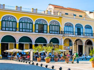 a yellow building with many people and a yellow building with many windows with Willemstad in the background