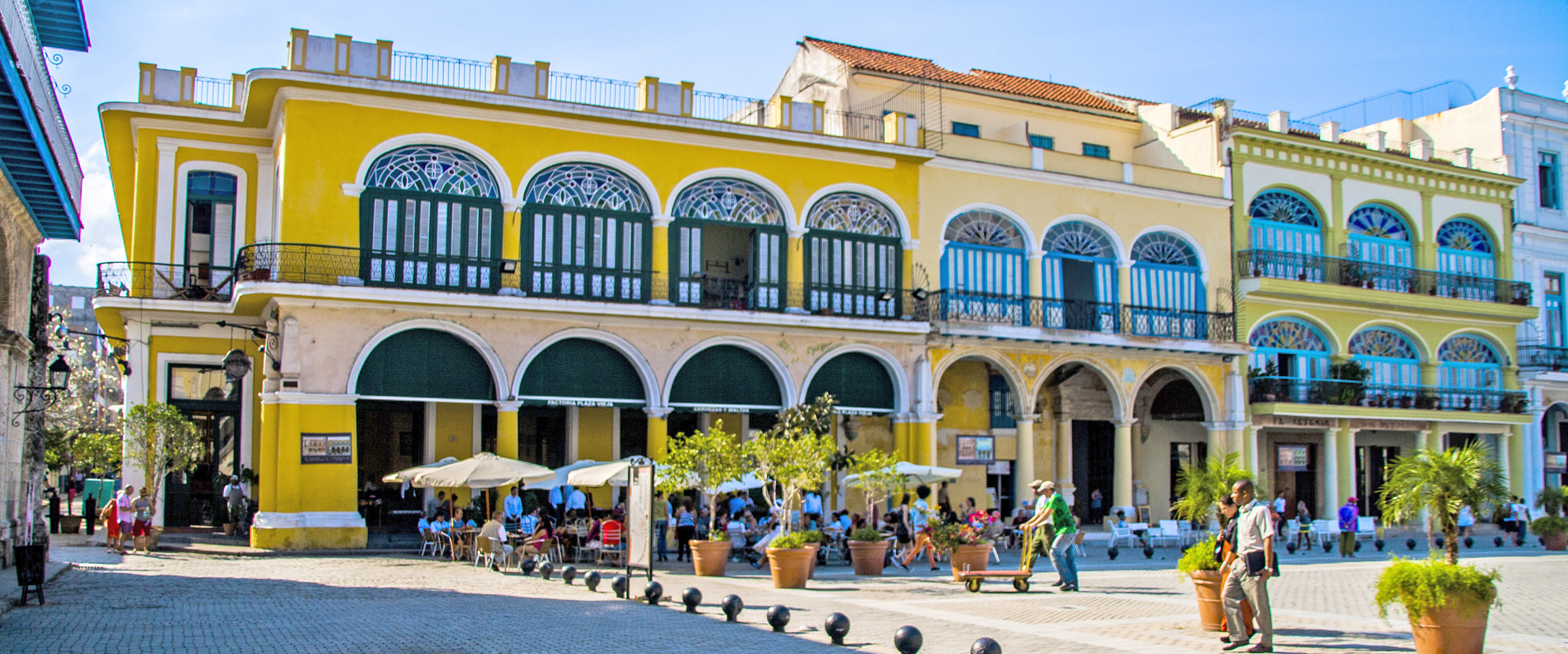 a yellow building with many people and a yellow building with many windows with Willemstad in the background