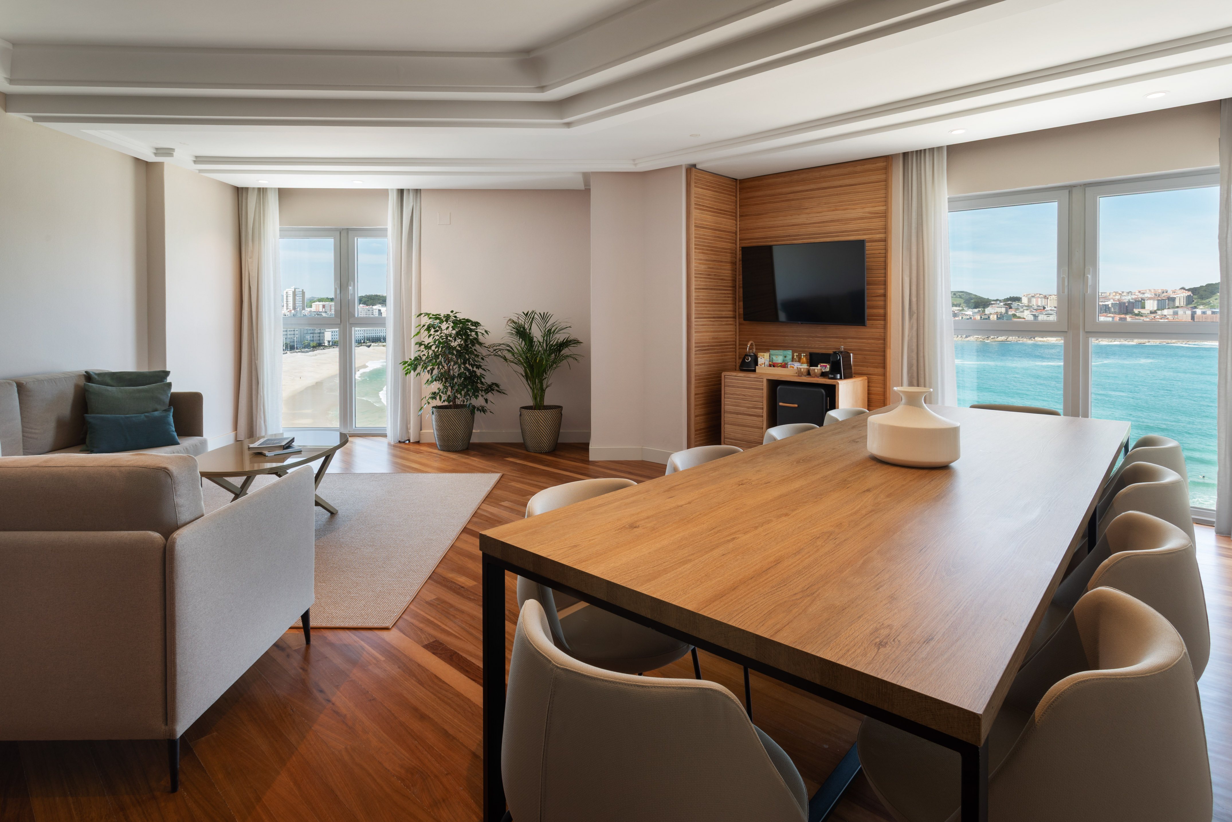 Modern living room and dining area with oceanfront beach view.