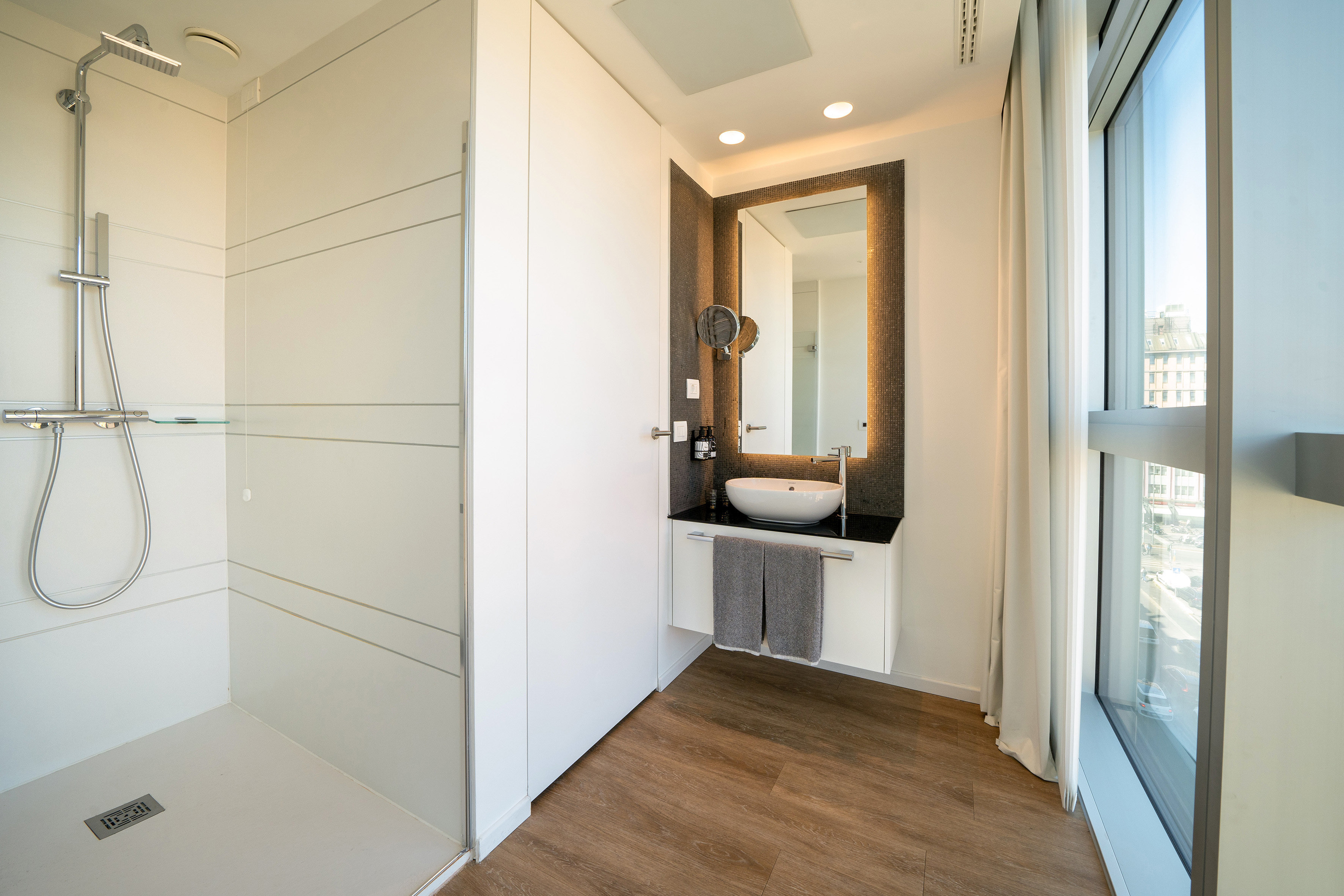 Modern bathroom with walk-in shower, vessel sink vanity, and lighted mirror.