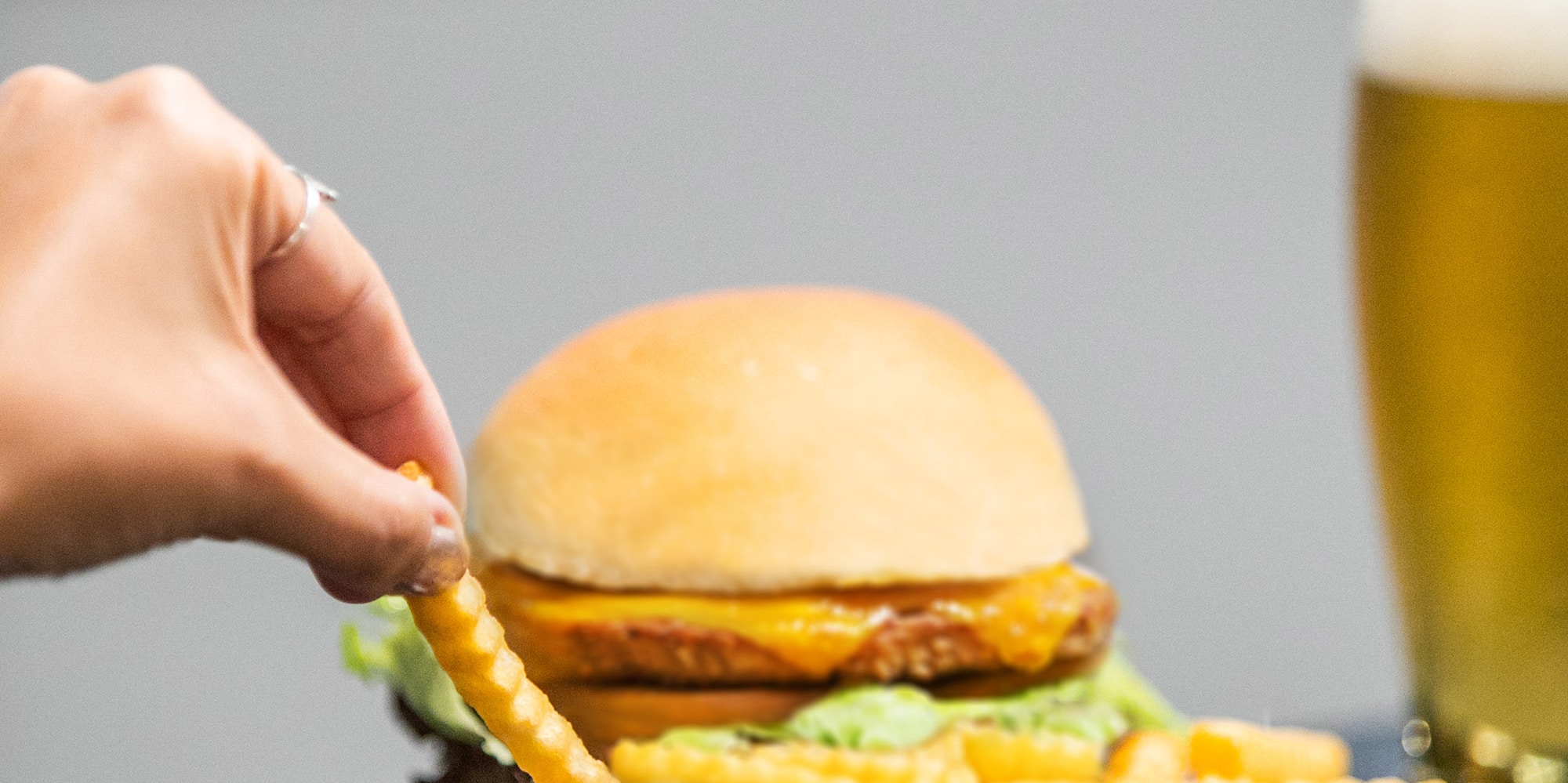 a hand dipping a french fries into a burger