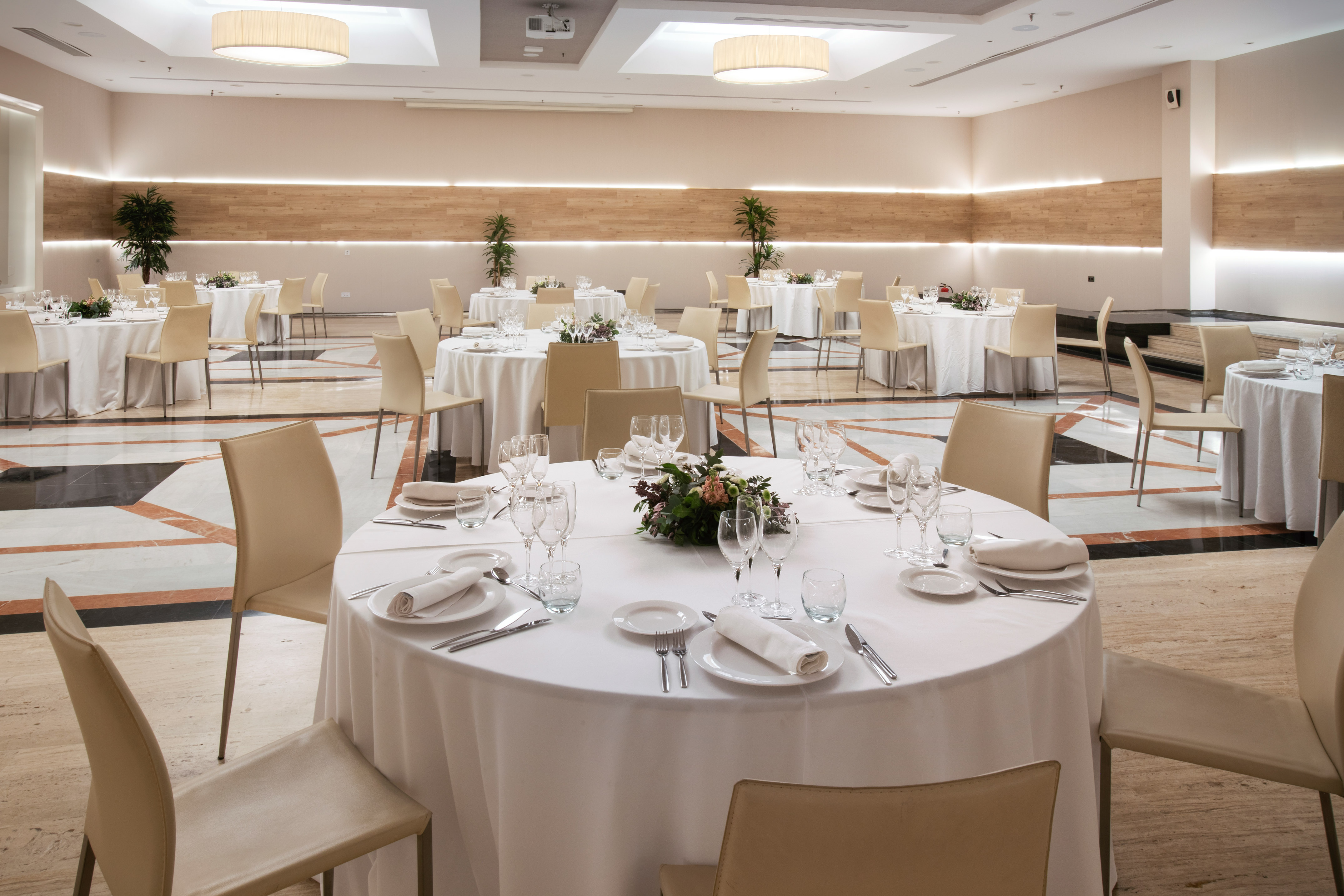 Elegant banquet hall with round tables, white linens, and floral centerpieces.