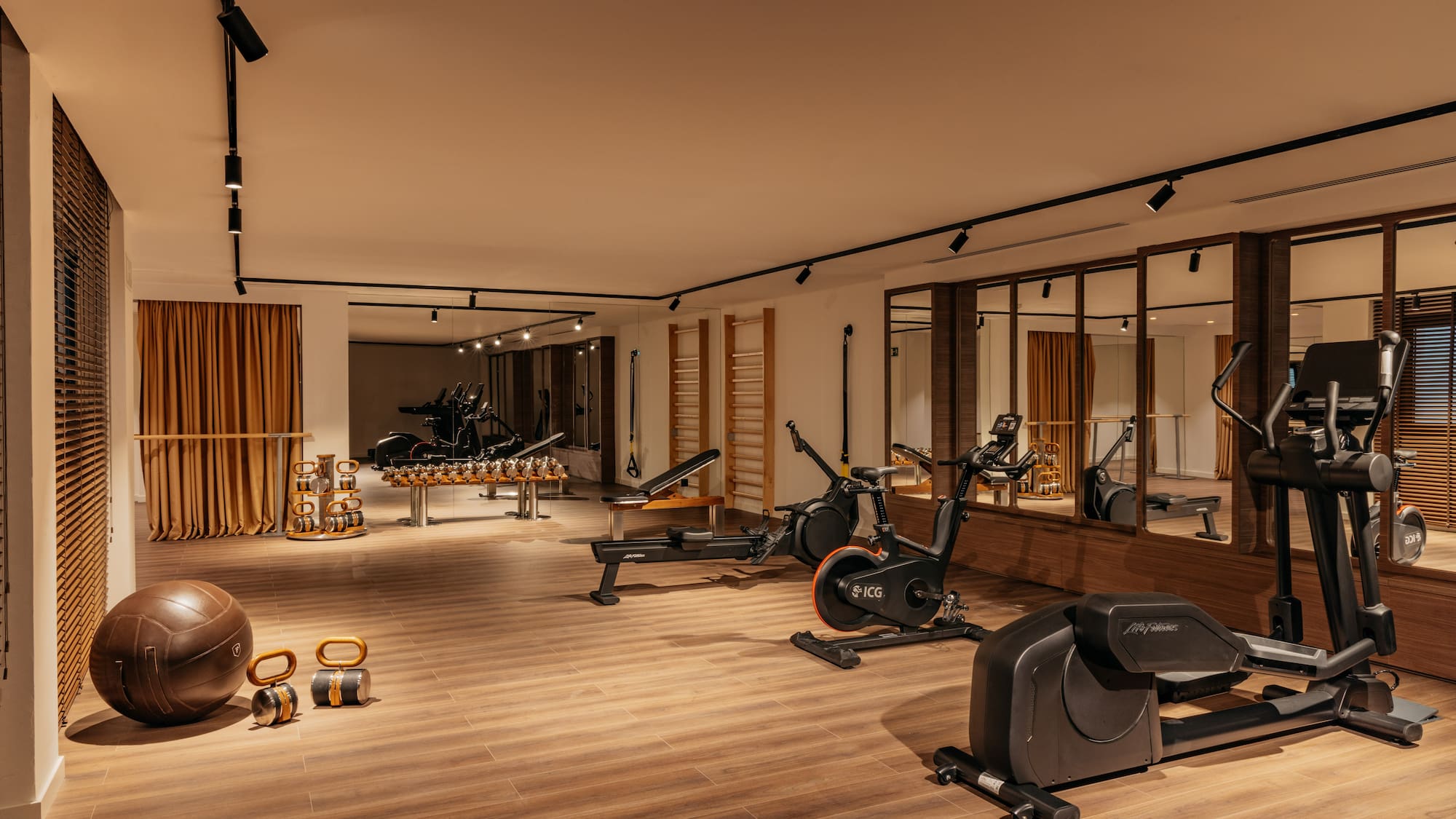 Modern gym with diverse exercise equipment, mirrored walls, and warm lighting