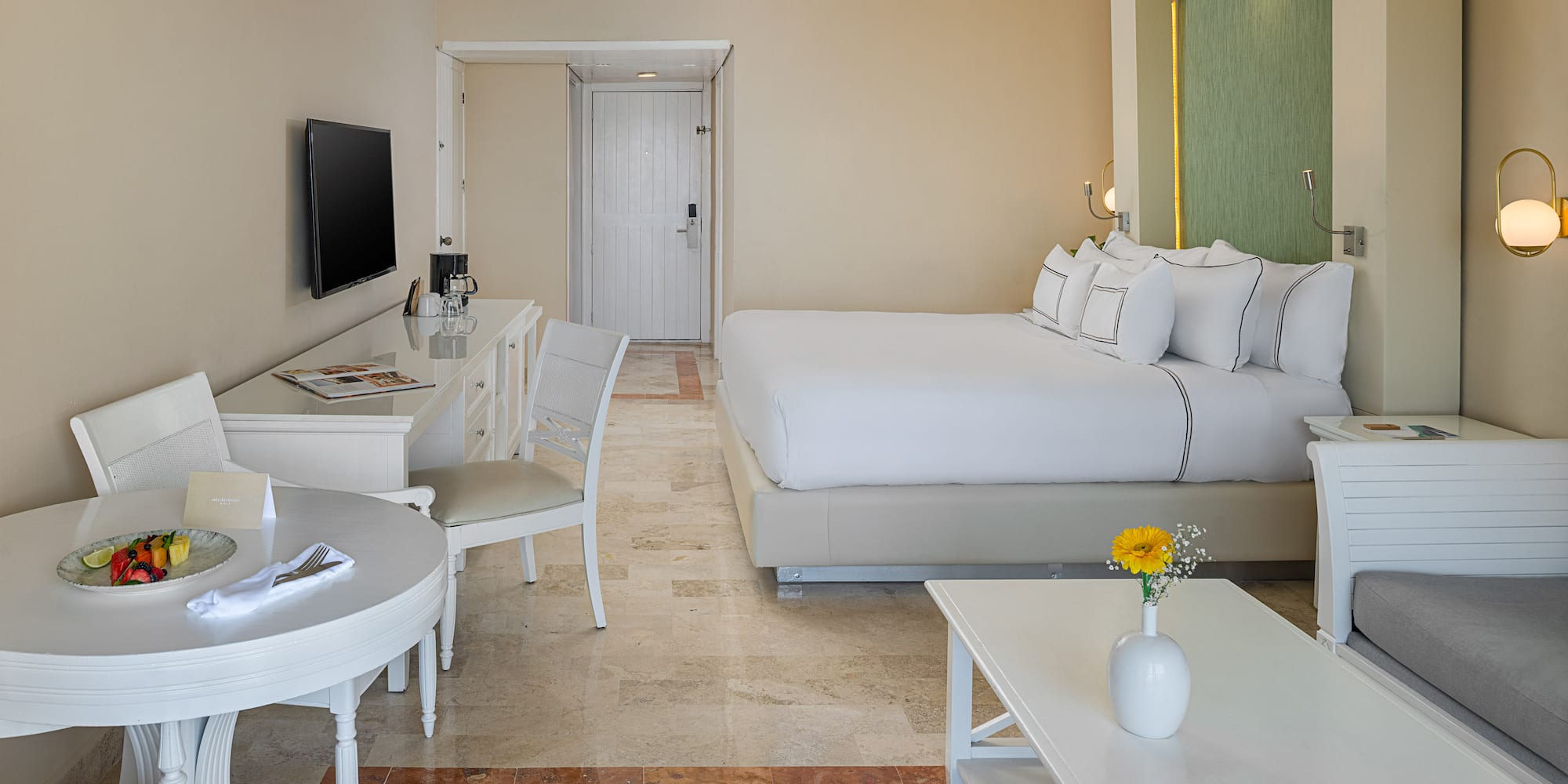 Spacious hotel room with king bed, dining area, sitting area, and modern decor.
