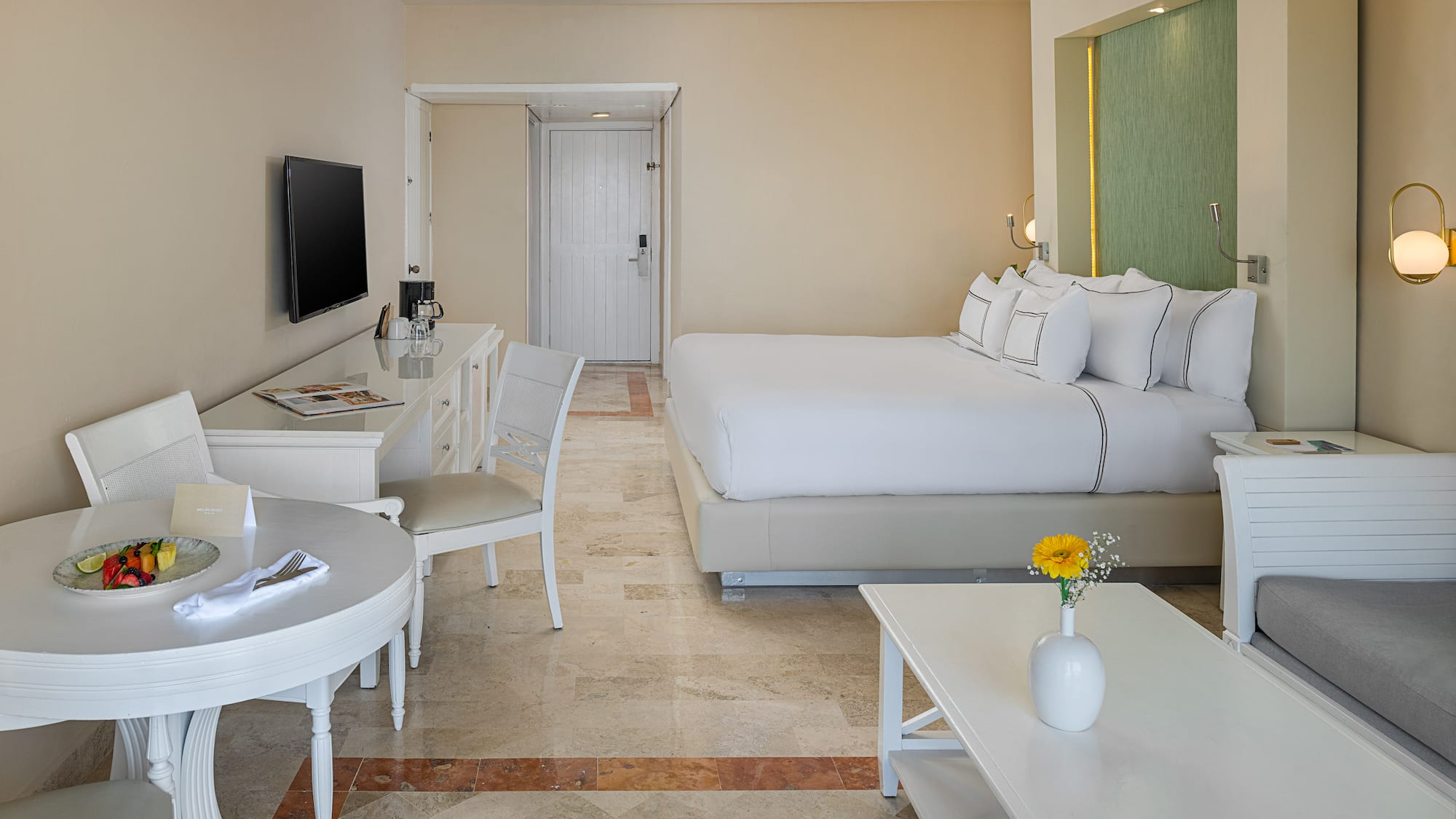 Spacious hotel room with king bed, dining area, sitting area, and modern decor.