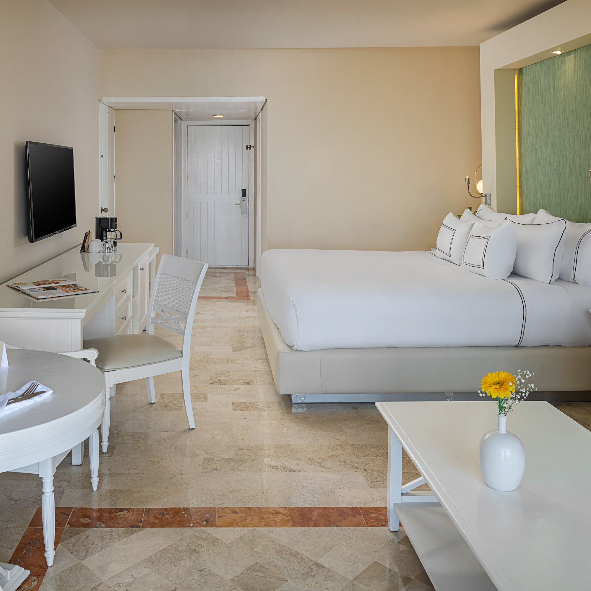 Spacious hotel room with king bed, dining area, sitting area, and modern decor.