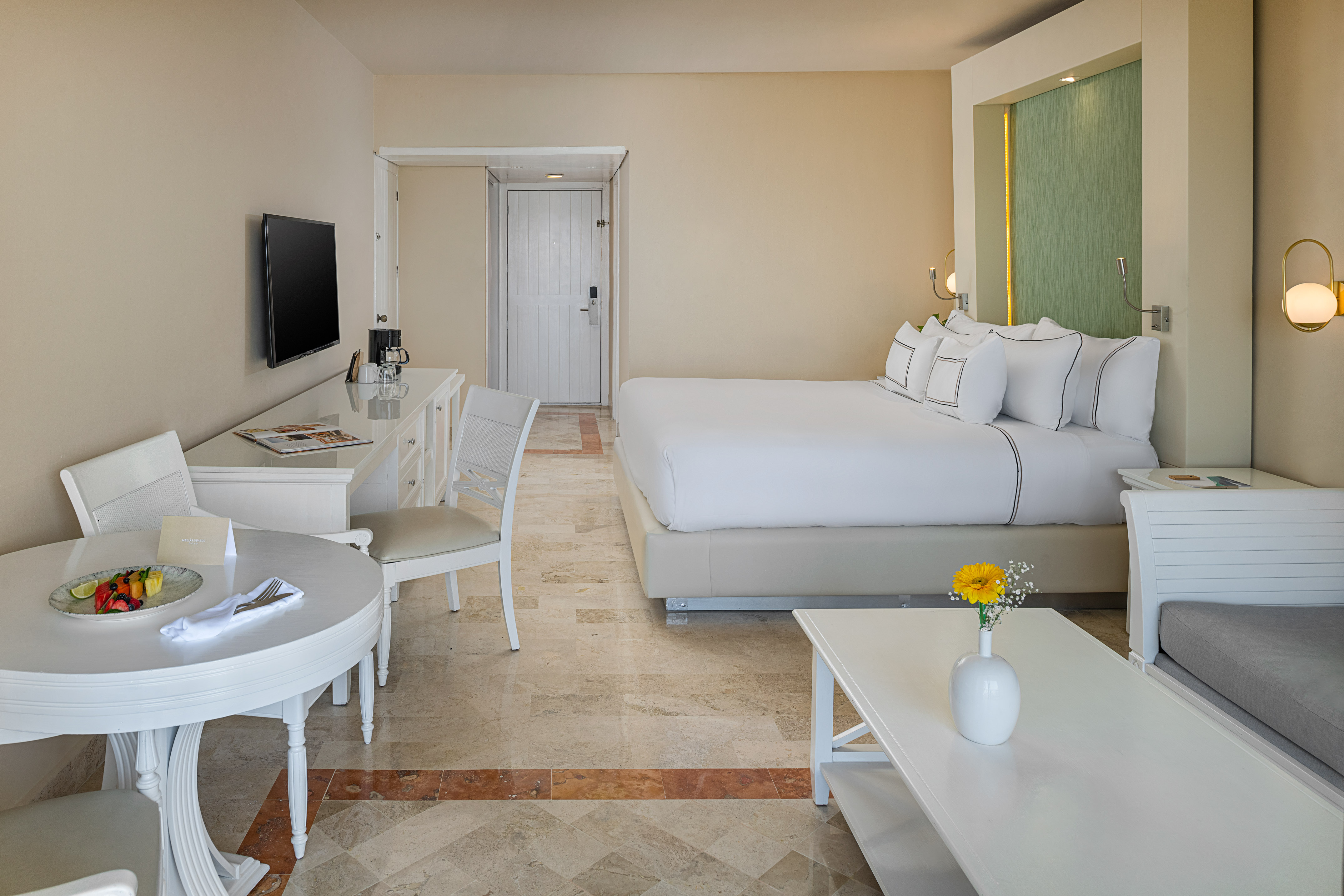 Spacious hotel room with king bed, dining area, sitting area, and modern decor.
