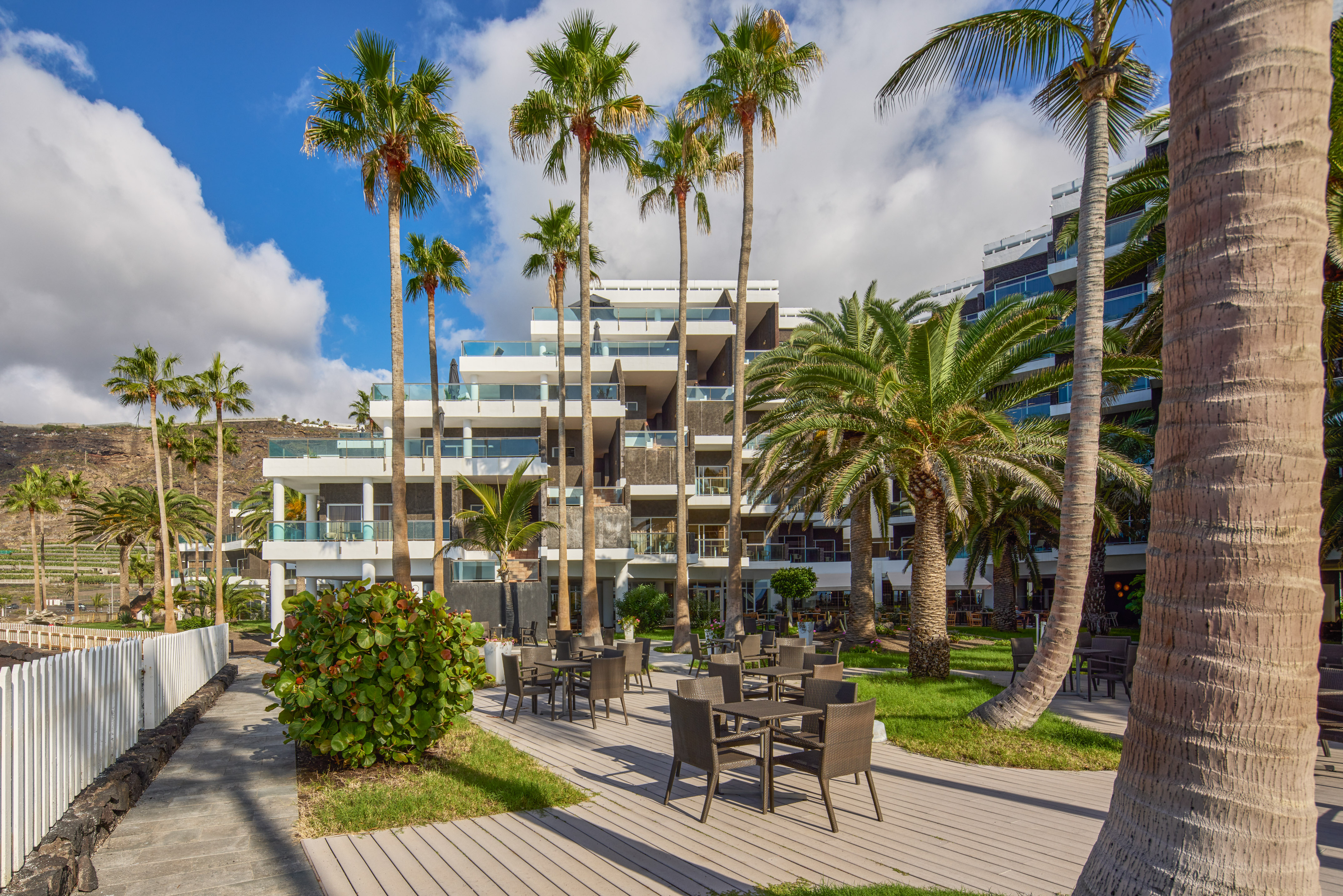 Modern resort hotel, tropical palm trees, outdoor dining terrace.