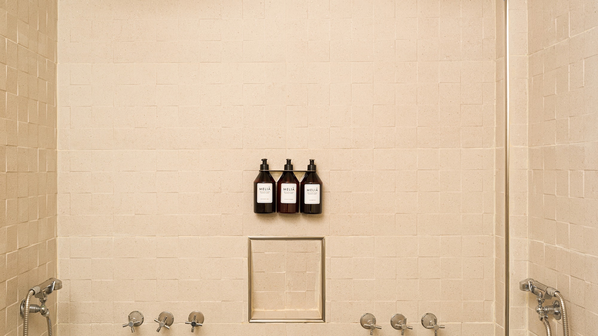 a shower with three faucets and a few bottles of liquid