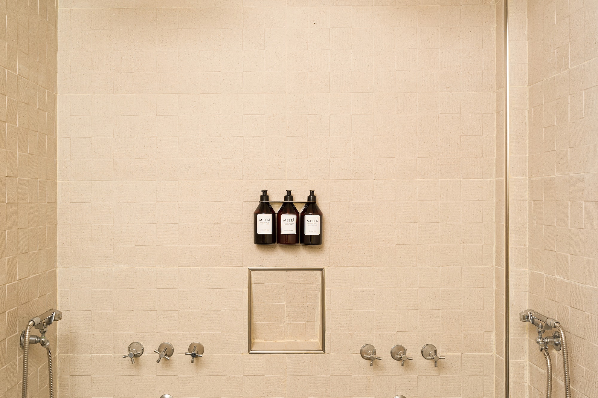 a shower with three faucets and a few bottles of liquid