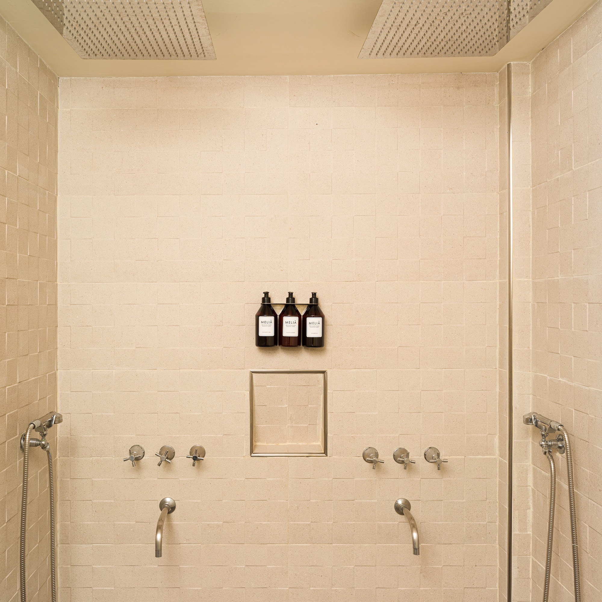 a shower with three faucets and a few bottles of liquid