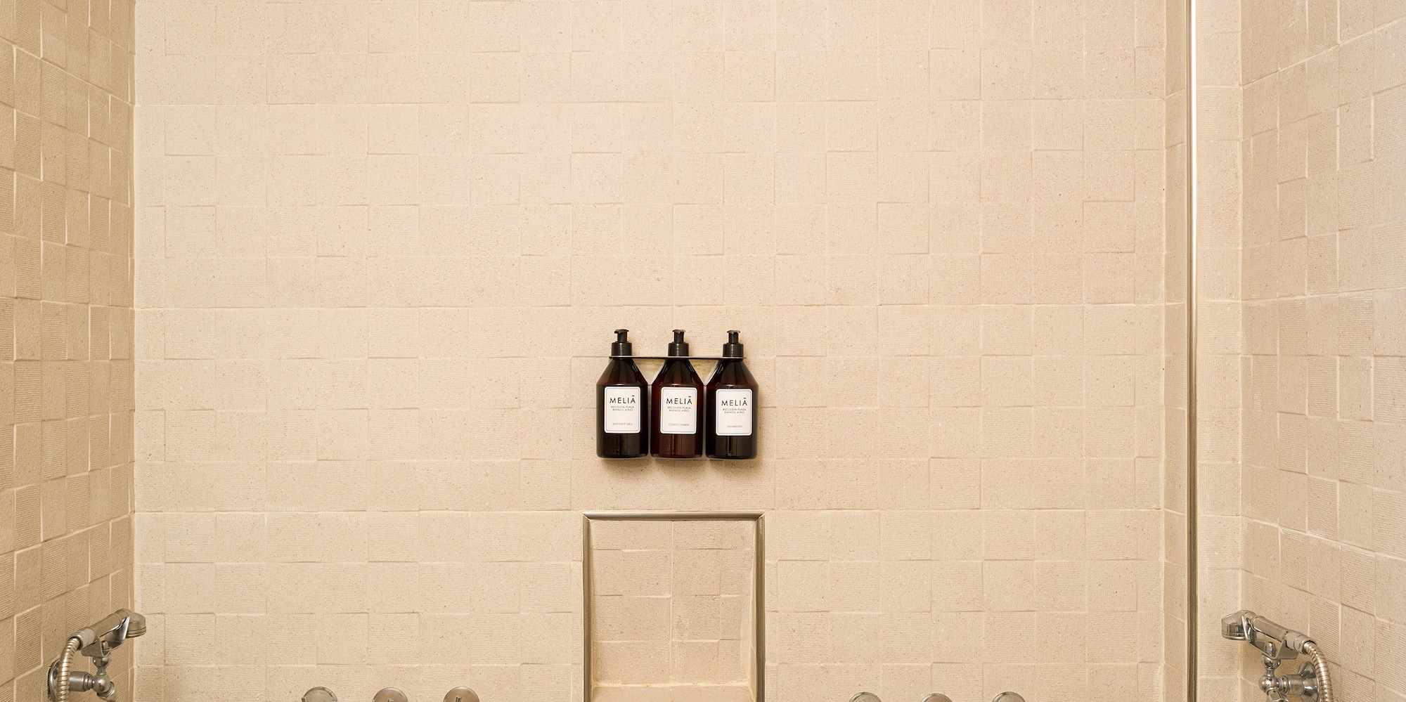 a shower with three faucets and a few bottles of liquid