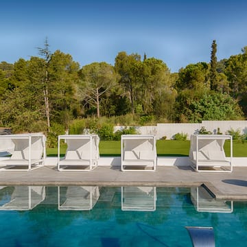 a pool with white chairs and trees in the background