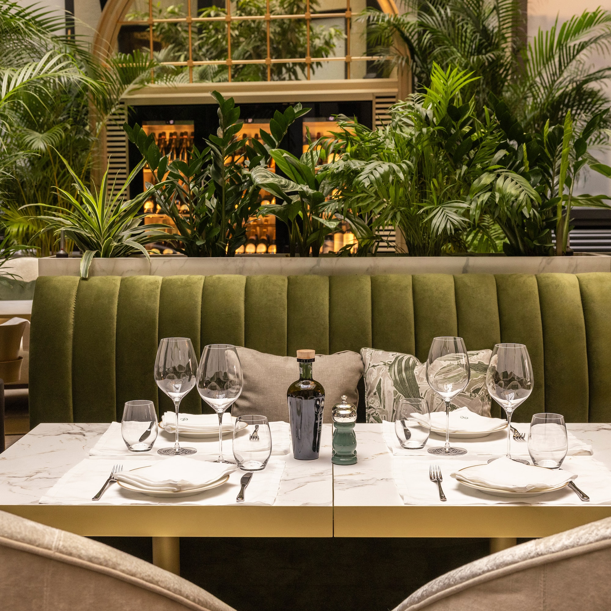 a table set for a dinner with a green couch and plants