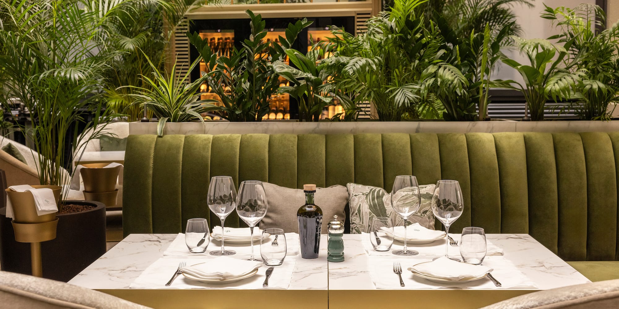 a table set for a dinner with a green couch and plants