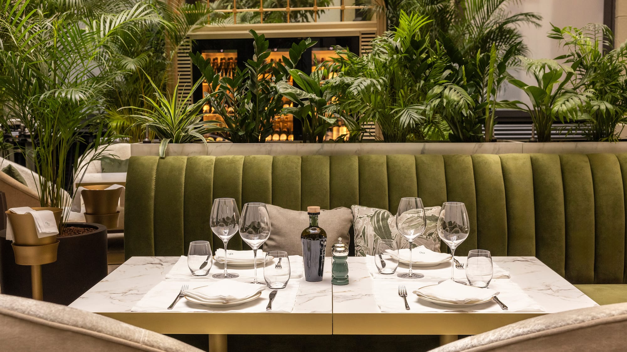 a table set for a dinner with a green couch and plants